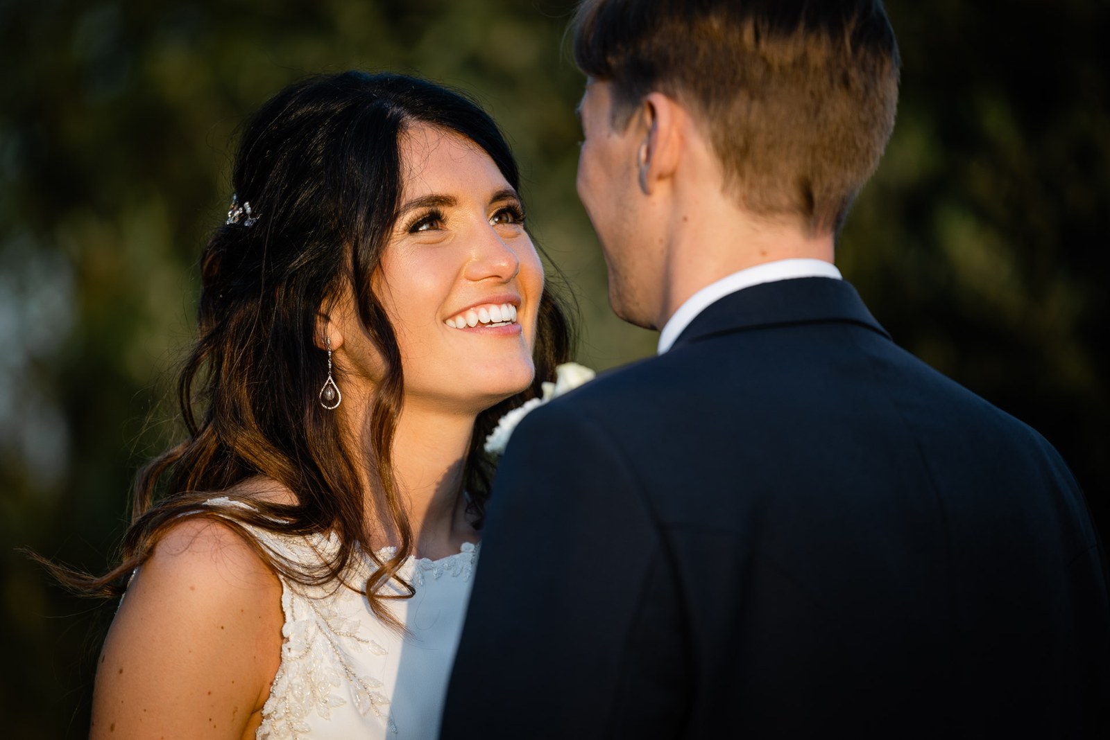 Close-up of the couple face to face, the bride smiling up at him in drop earrings
