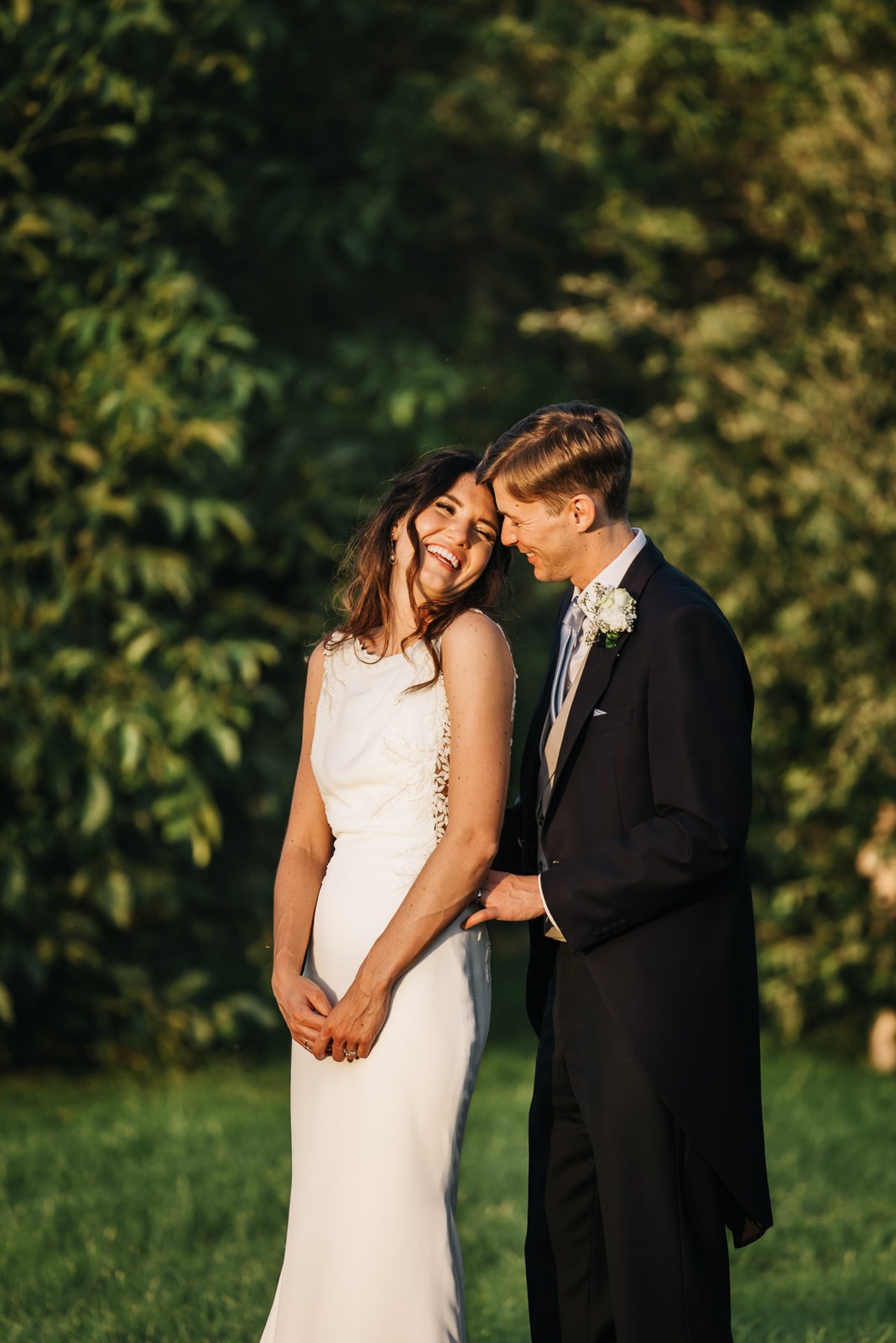 The newlyweds holding one another on the lawn as the light fades