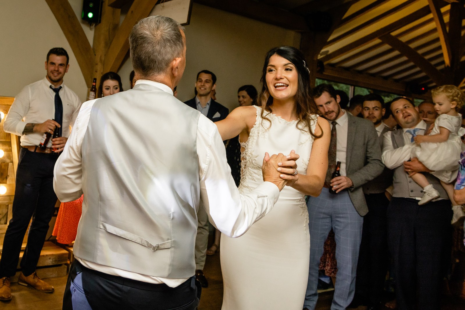 The bride dancing with a guest in a waistcoat as friends look on