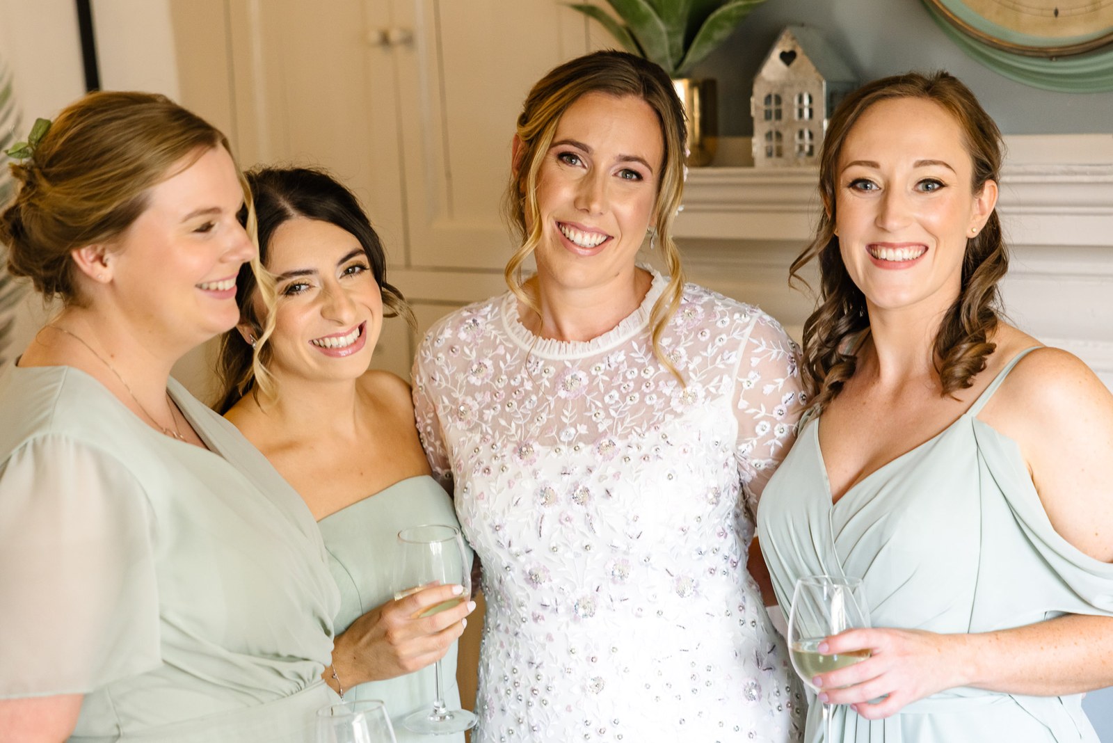 The bride laughing with her bridesmaids, champagne in hand, before the ceremony