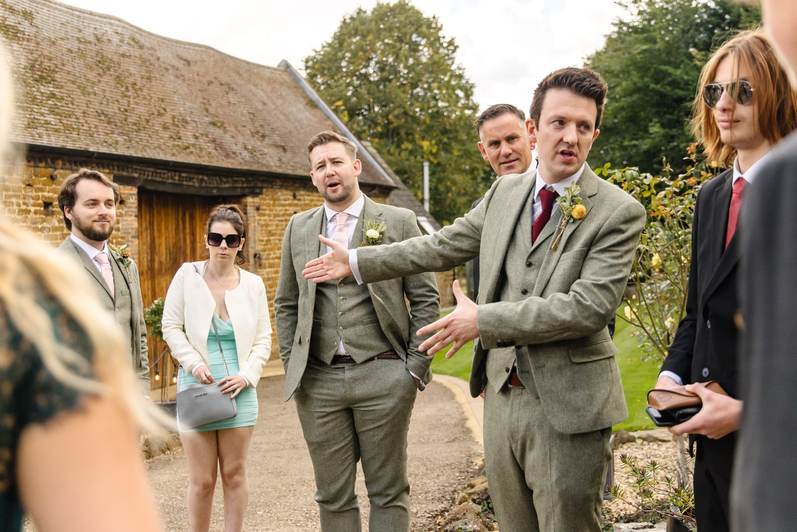 Groom greeting arriving guests on the gravel path outside the barn at Dovecote Events