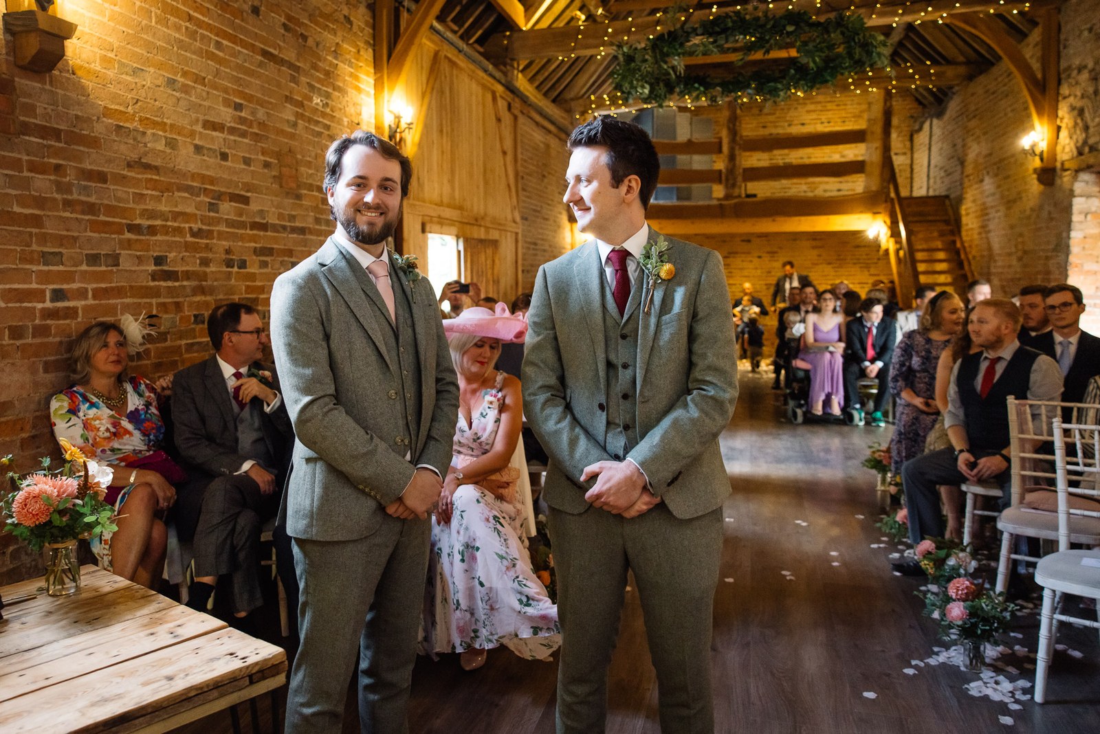 Groom and best man waiting at the front of the brick ceremony barn at Dovecote Events