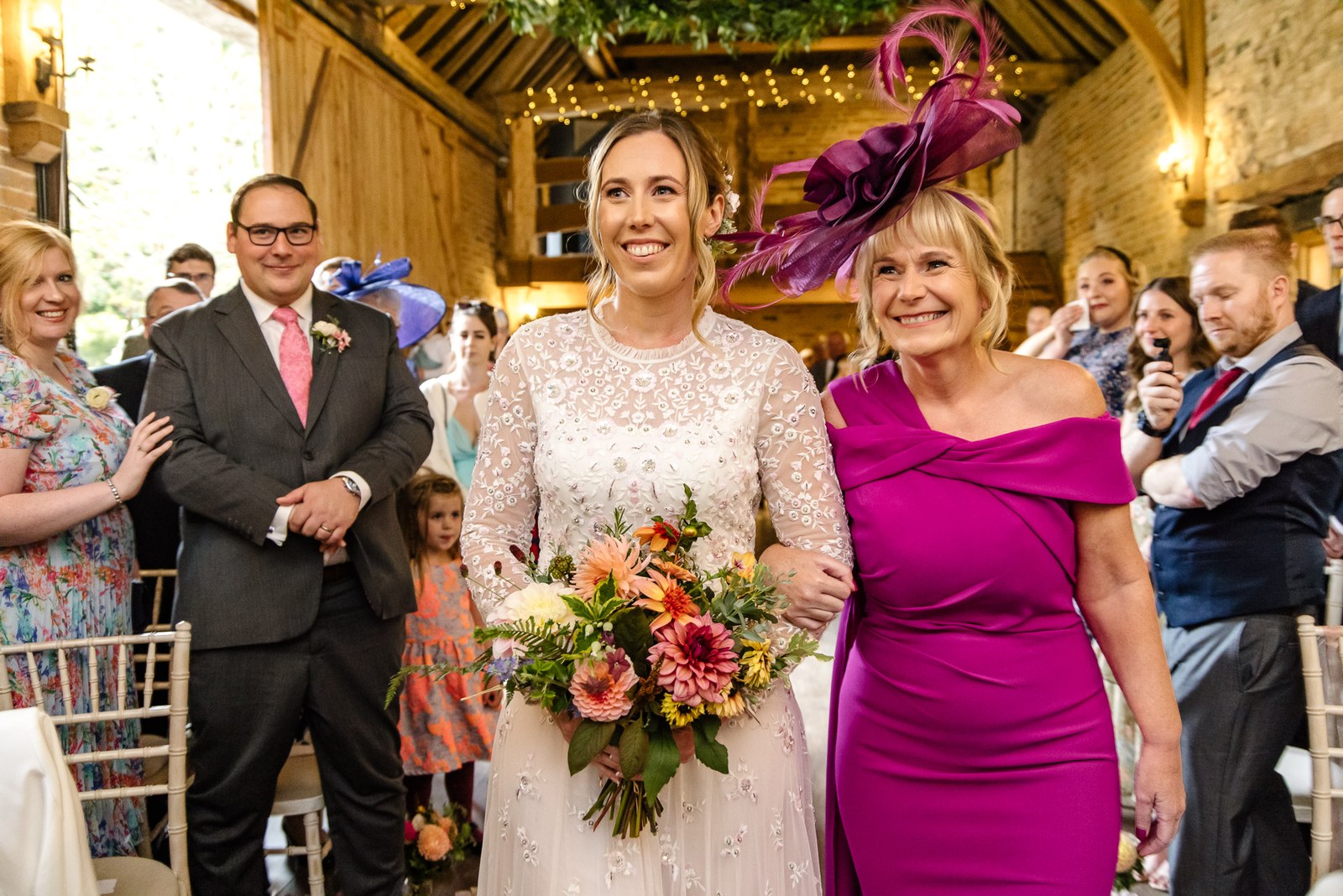 Bride walking the aisle on an escort's arm through the brick barn at Dovecote Events