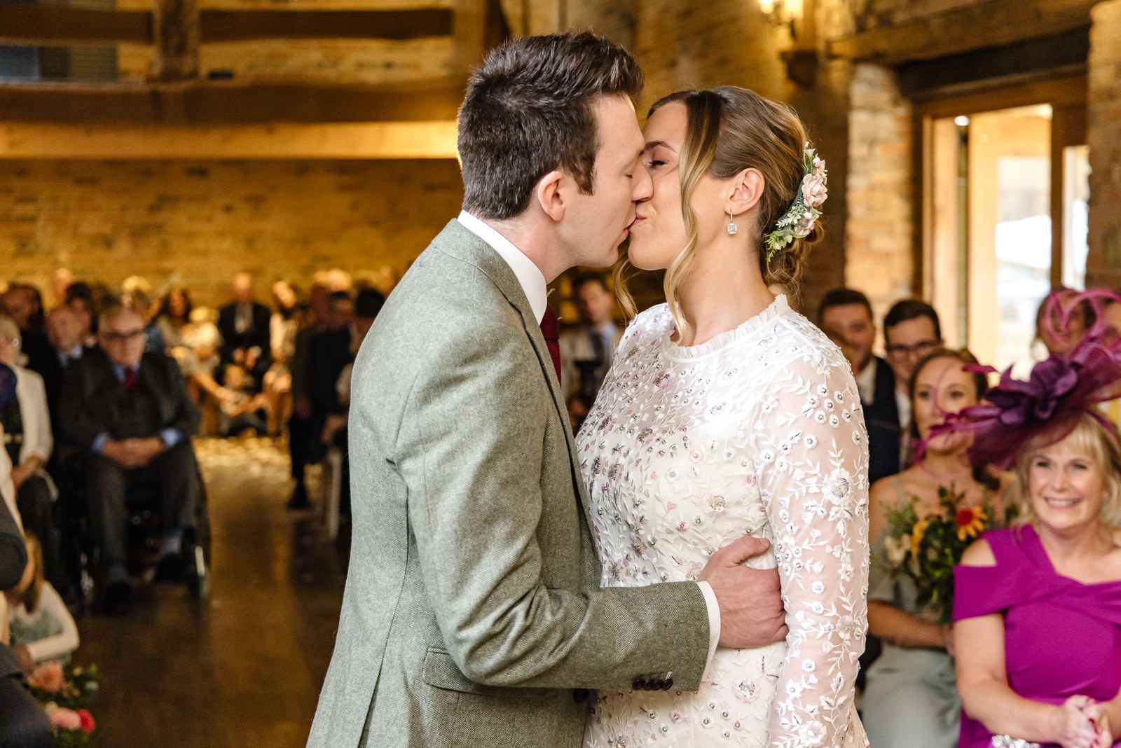 The couple's first kiss as newlyweds while guests applaud in the barn