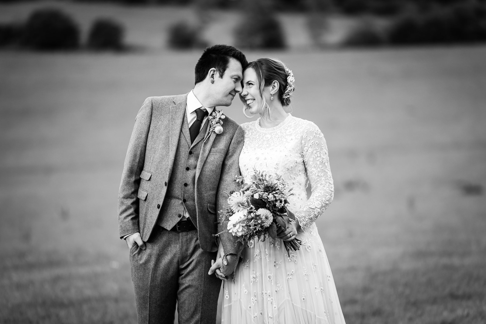 Black-and-white portrait of the couple before open countryside at Dovecote Events