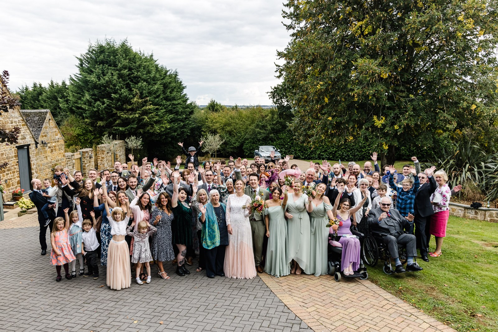 The full wedding party gathered on the driveway outside the venue at Dovecote Events