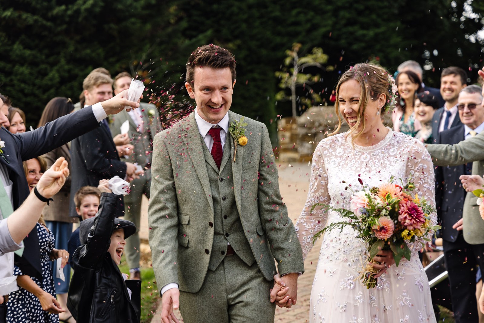 Newlyweds showered with confetti by guests, the bride clutching her bouquet