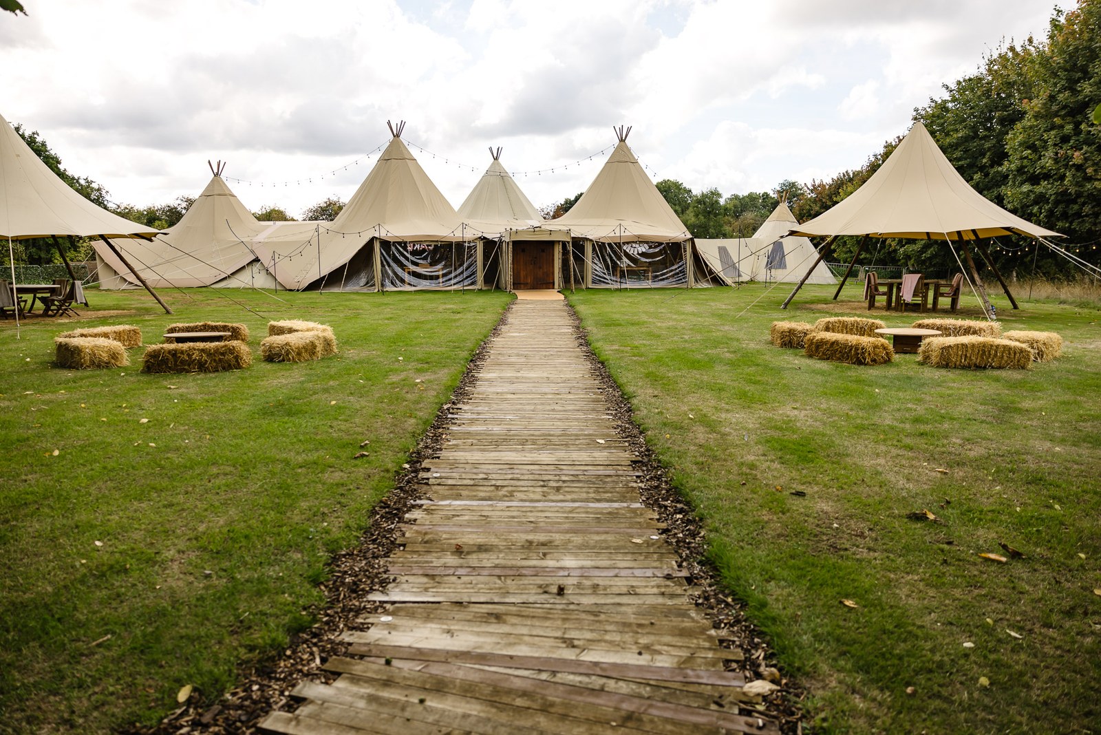 The tipi tents at Dovecote Events, a wooden boardwalk crossing the lawn to the entrance
