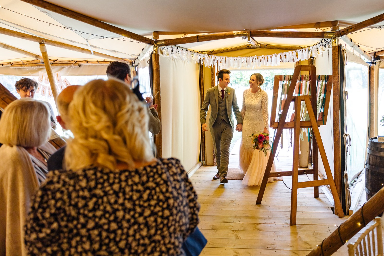Bride and groom entering the tipi reception at Dovecote Events as guests watch