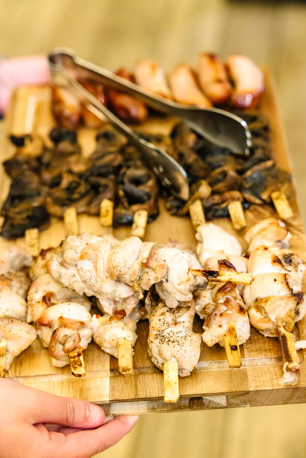Close-up of a sharing board of skewers and grilled meats carried to the tables