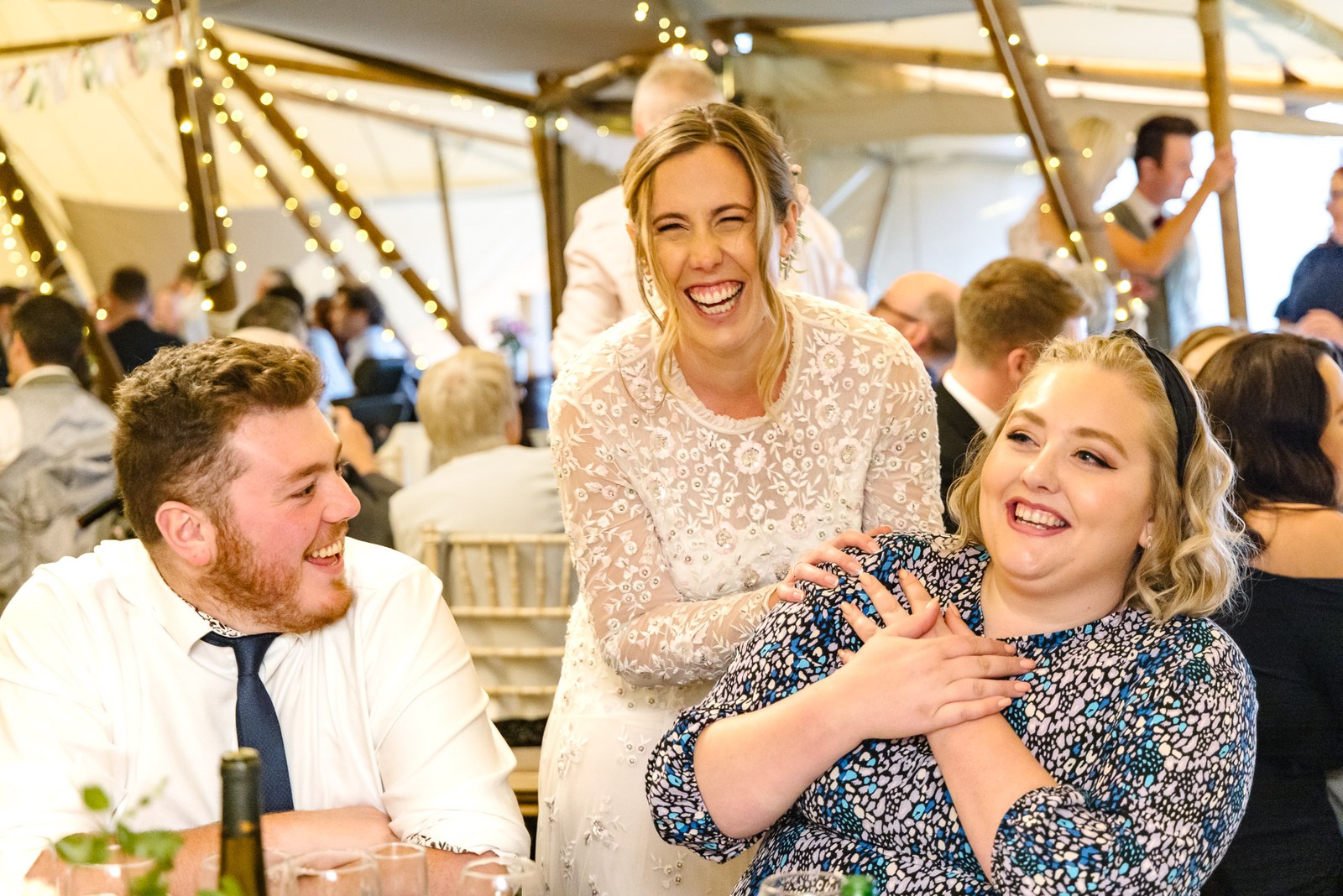 The bride laughing with two guests during the tipi reception