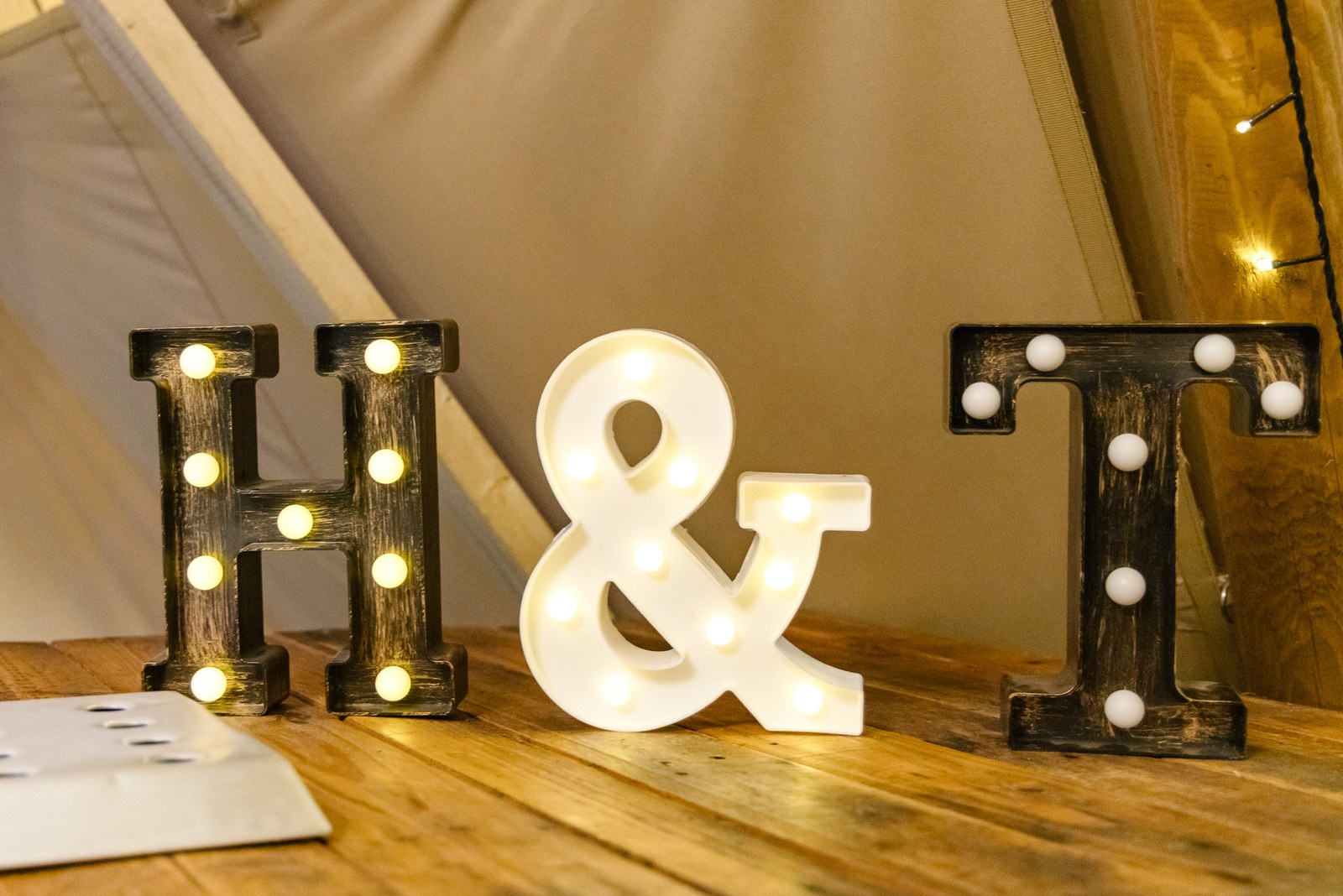The couple's illuminated marquee-light initials standing on the wooden floor