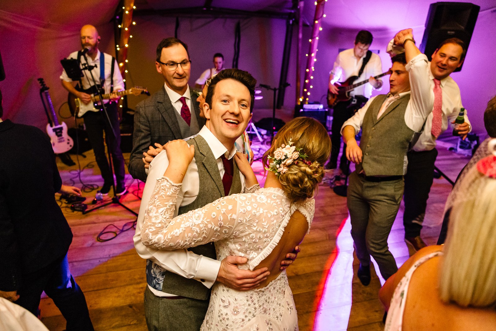 The newlyweds dancing among their guests as the band performs under coloured lights