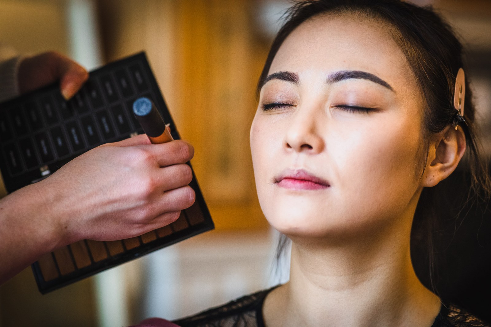 The bride having her makeup applied, eyes gently closed