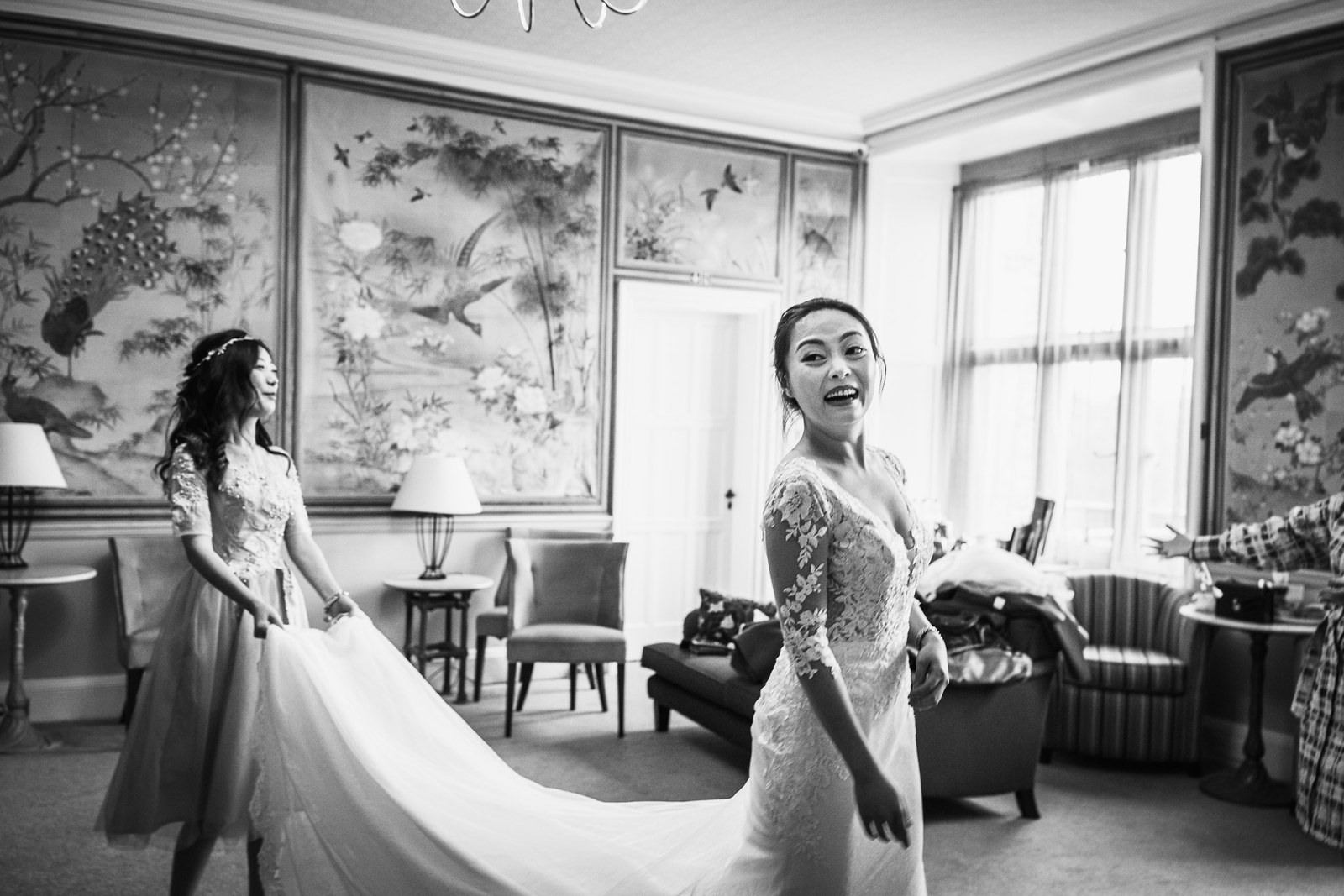 Black-and-white of the bride turning with her gown train fanned across the floor