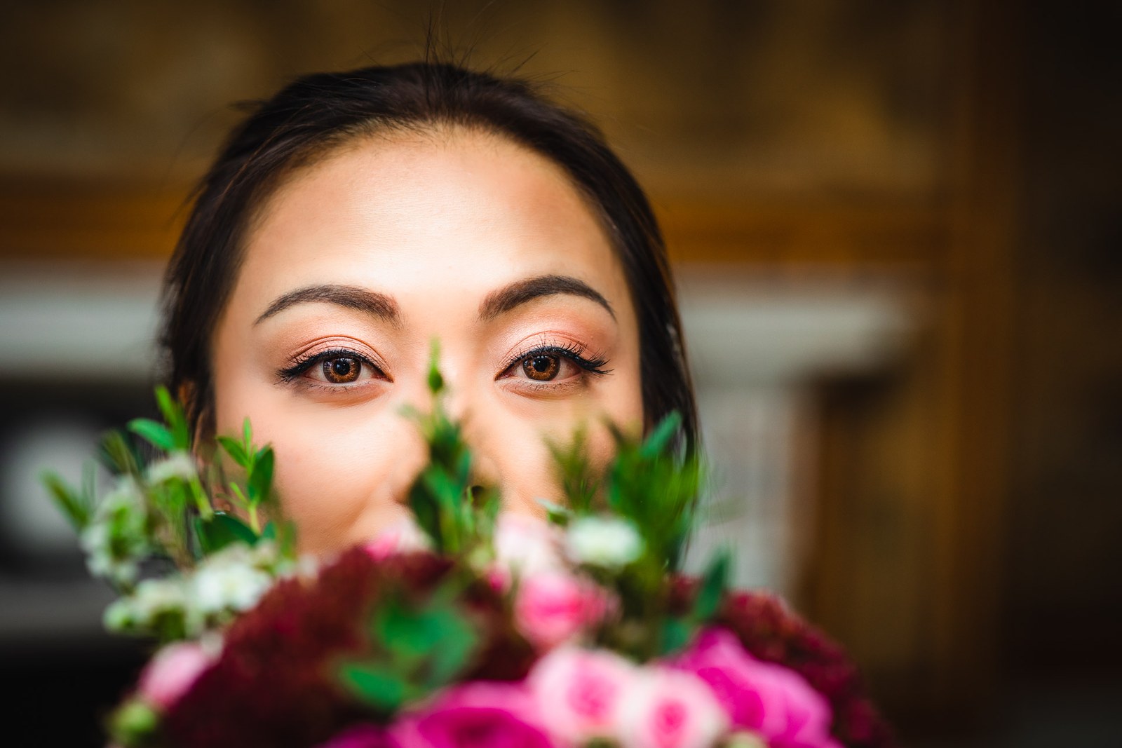 The bride's eyes above a bouquet of pink and burgundy roses