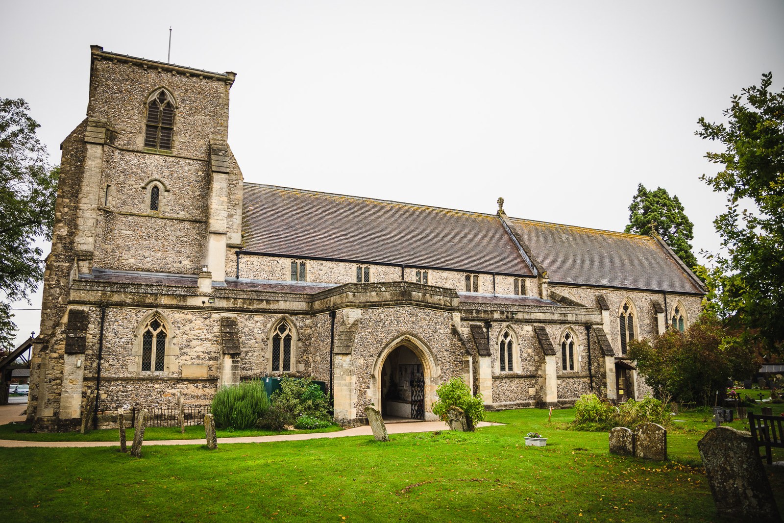 The flint tower and graveyard of the parish church on a grey morning