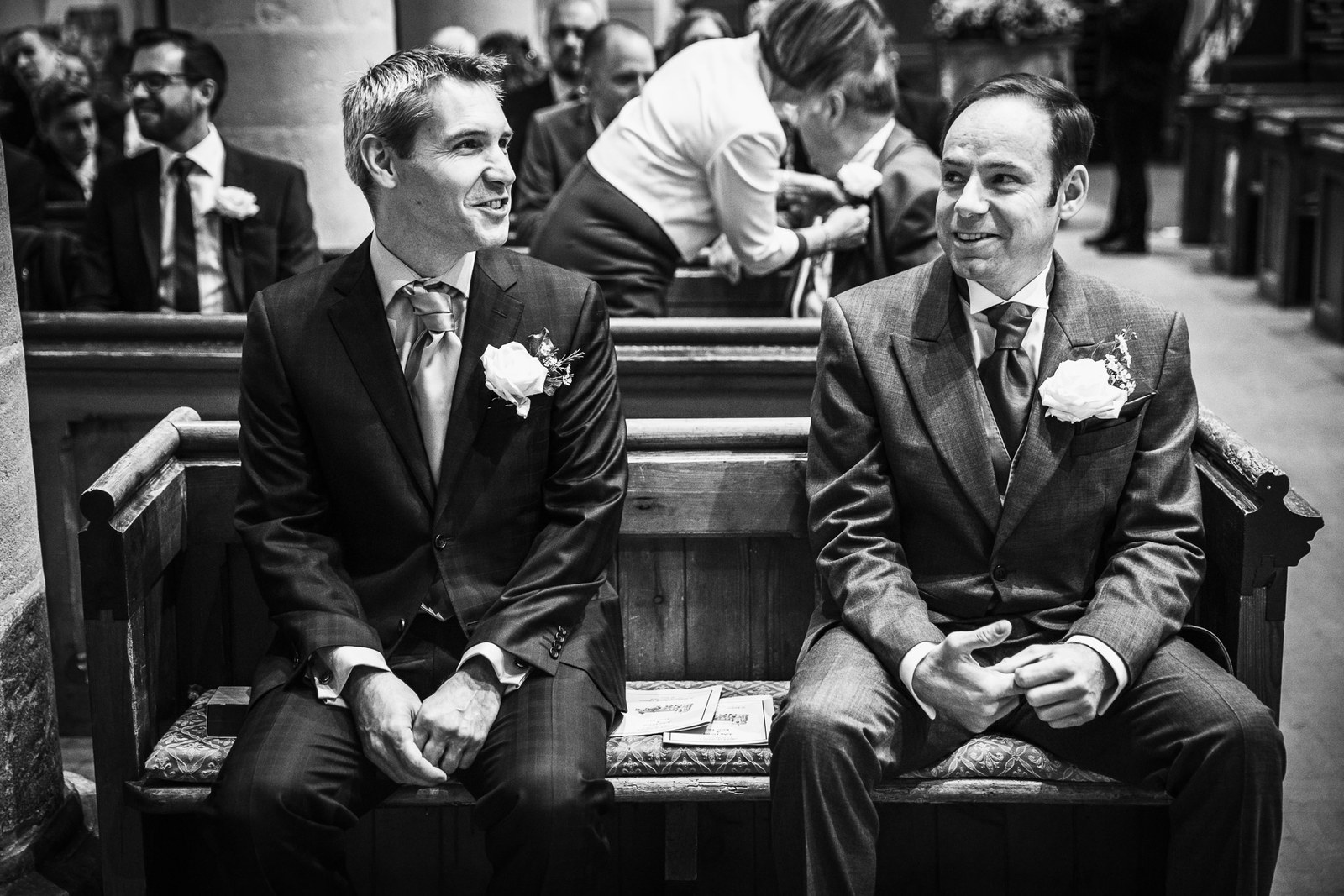 Black-and-white of the groom and best man waiting in a pew before the ceremony