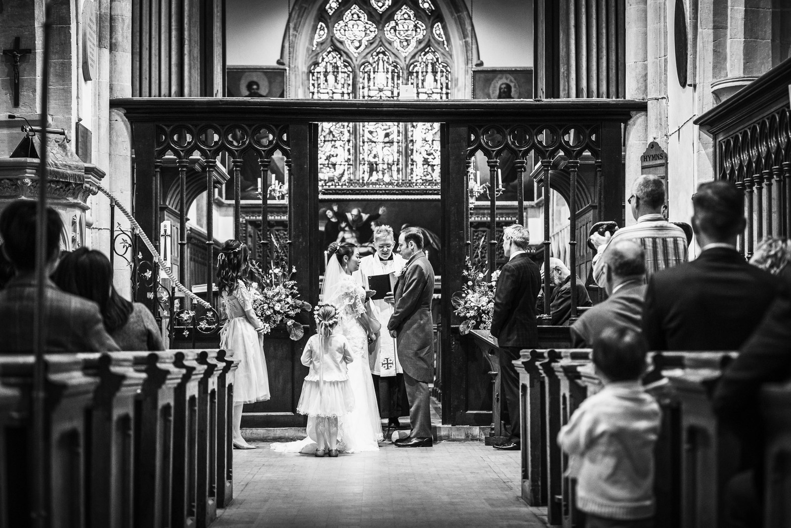 Black-and-white of the couple at the altar framed by the carved chancel screen