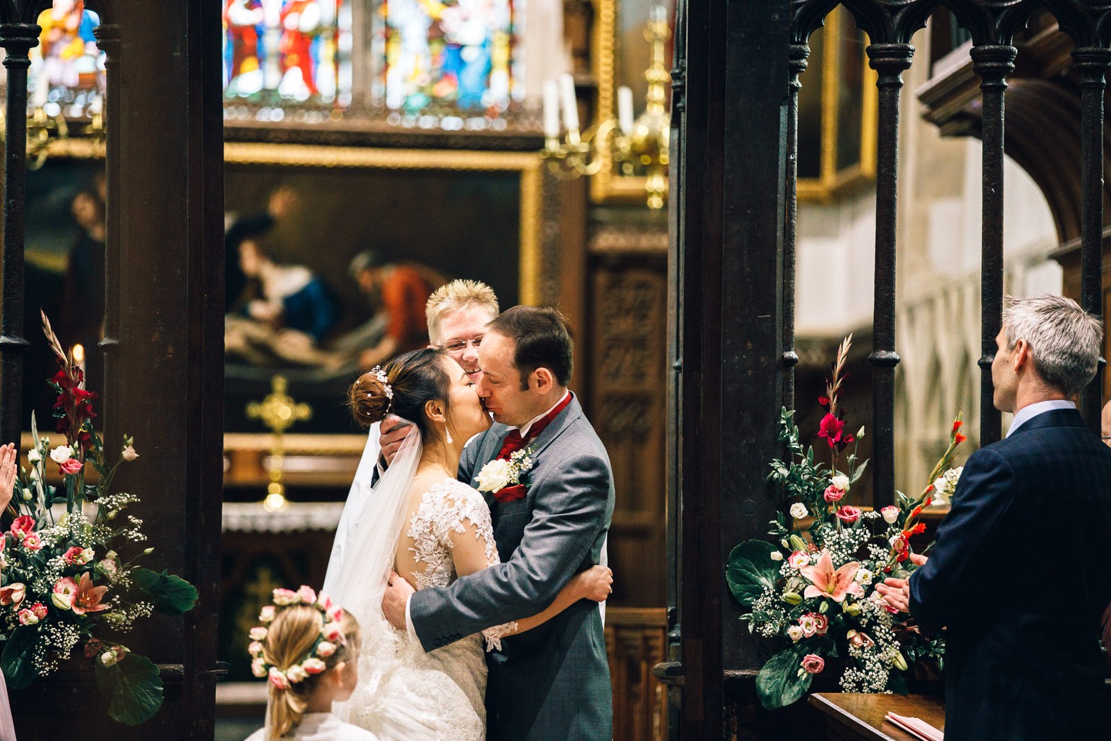 The couple's first kiss at the altar, a flower girl below and flowers all around