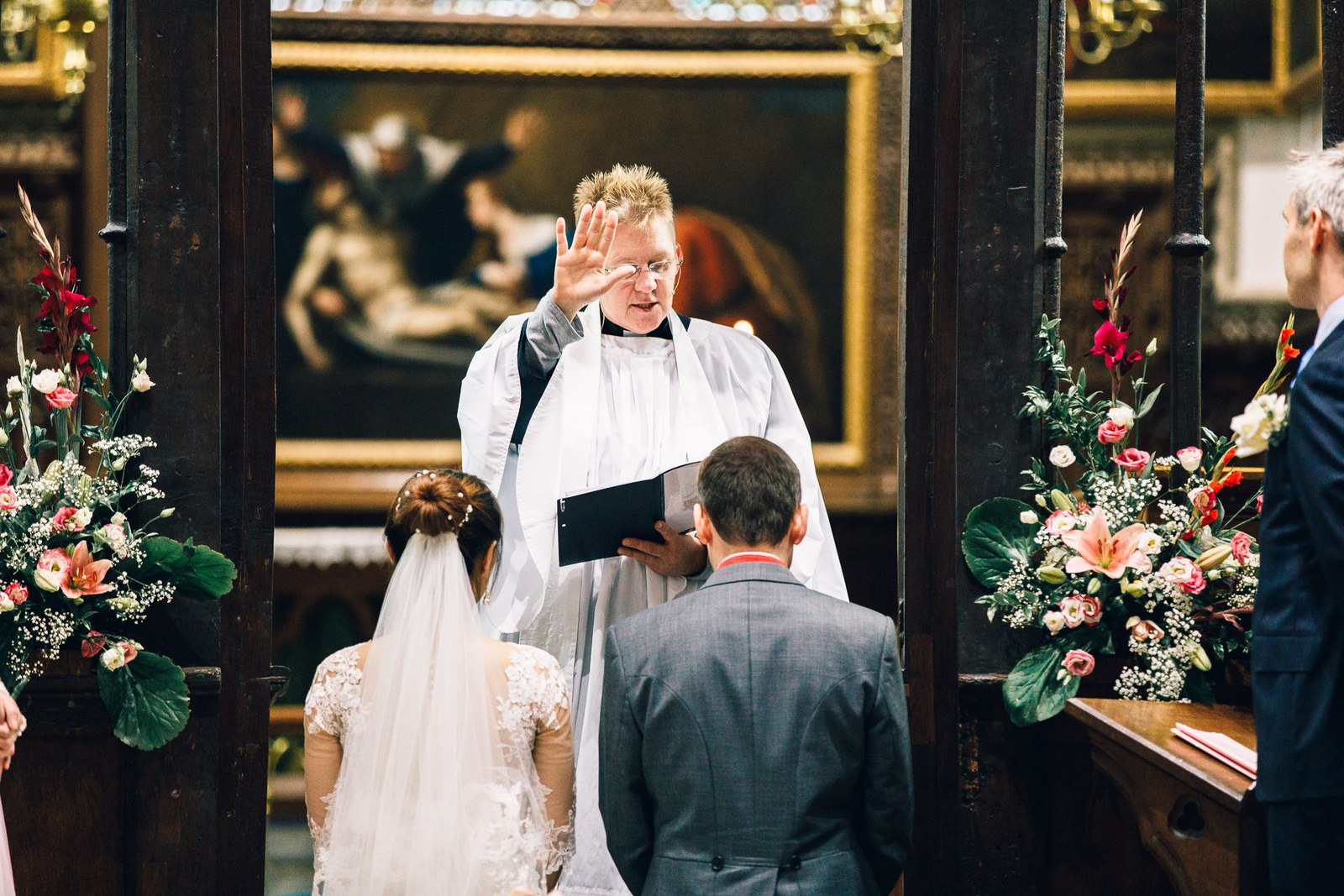 The vicar raising a hand in blessing over the couple at the altar