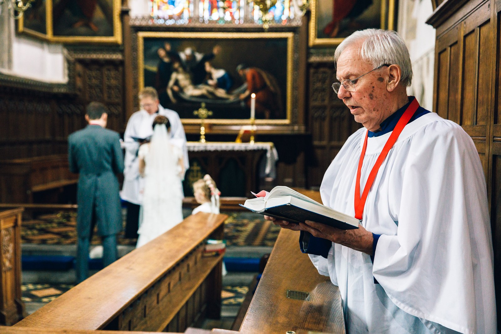A robed reader with the prayer book, the couple standing at the altar beyond