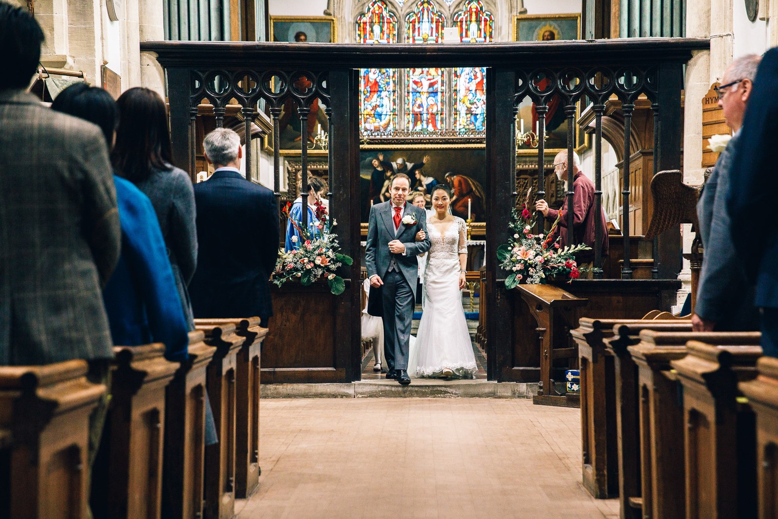 Newlyweds walking back through the carved chancel screen after the service