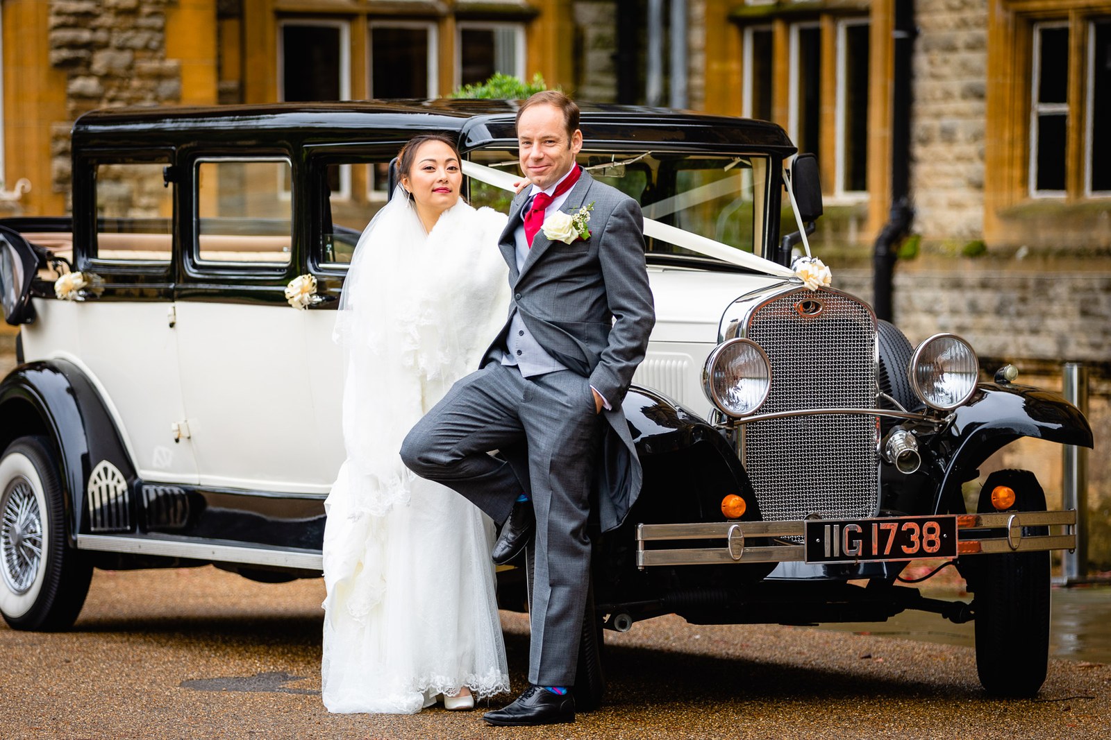 The couple posing with the vintage car in front of Eynsham Hall