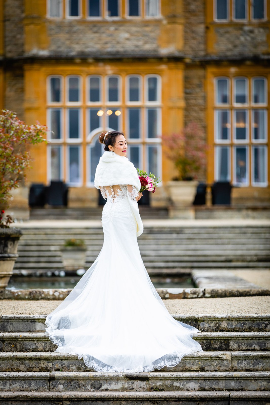 Bride with her dress train fanned across the stone steps of Eynsham Hall