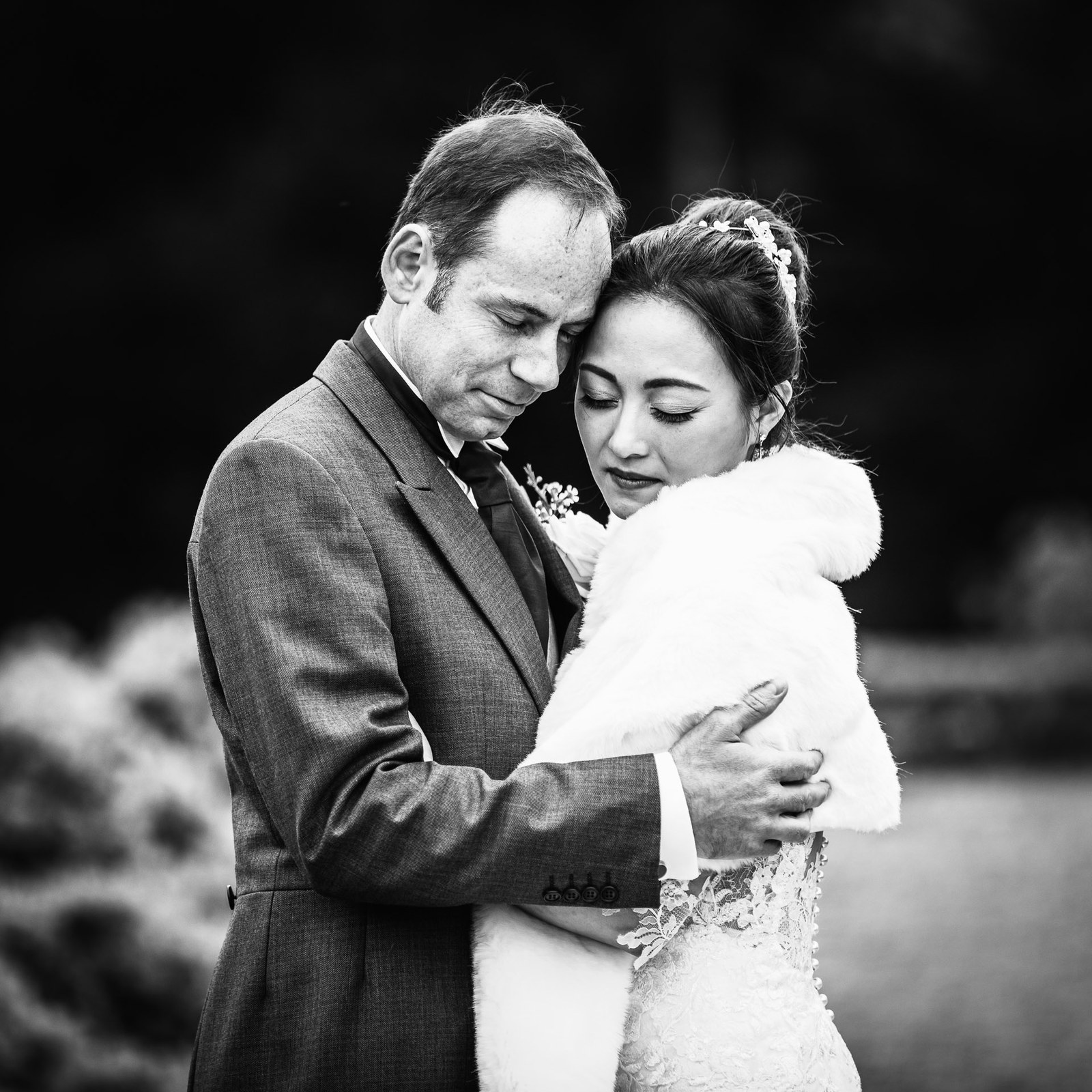 Black-and-white of the couple in a tender embrace, the bride resting on his shoulder