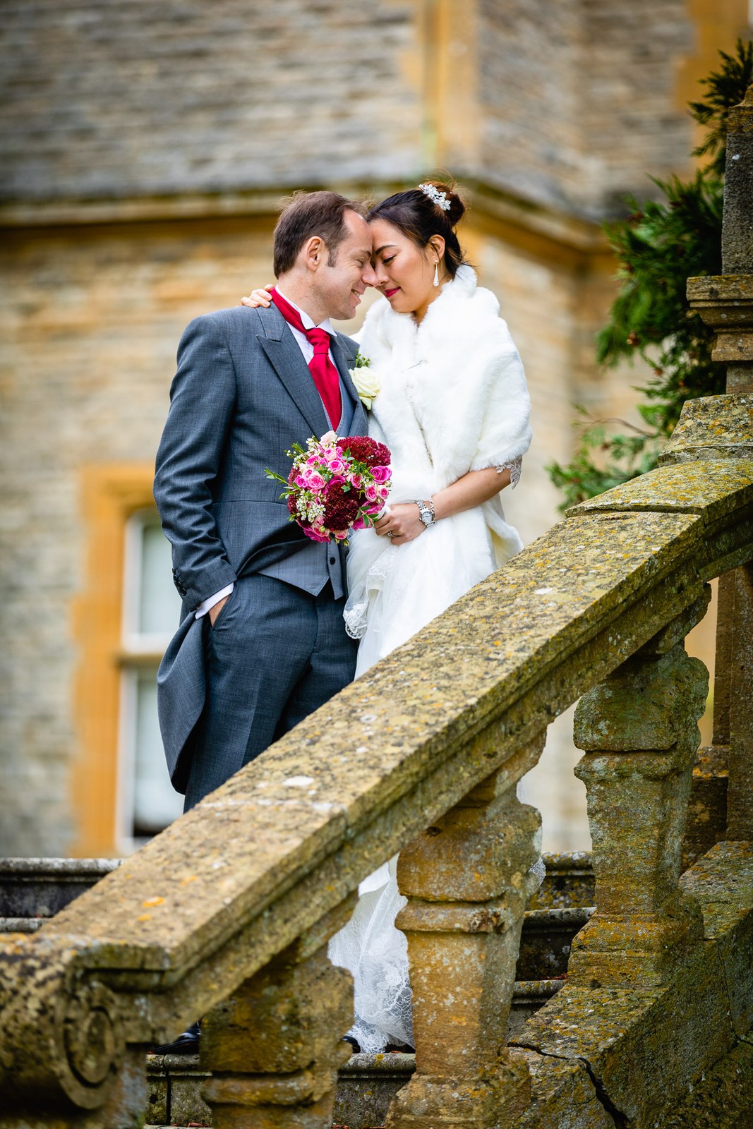 The couple on the balustraded stone staircase at Eynsham Hall, foreheads together