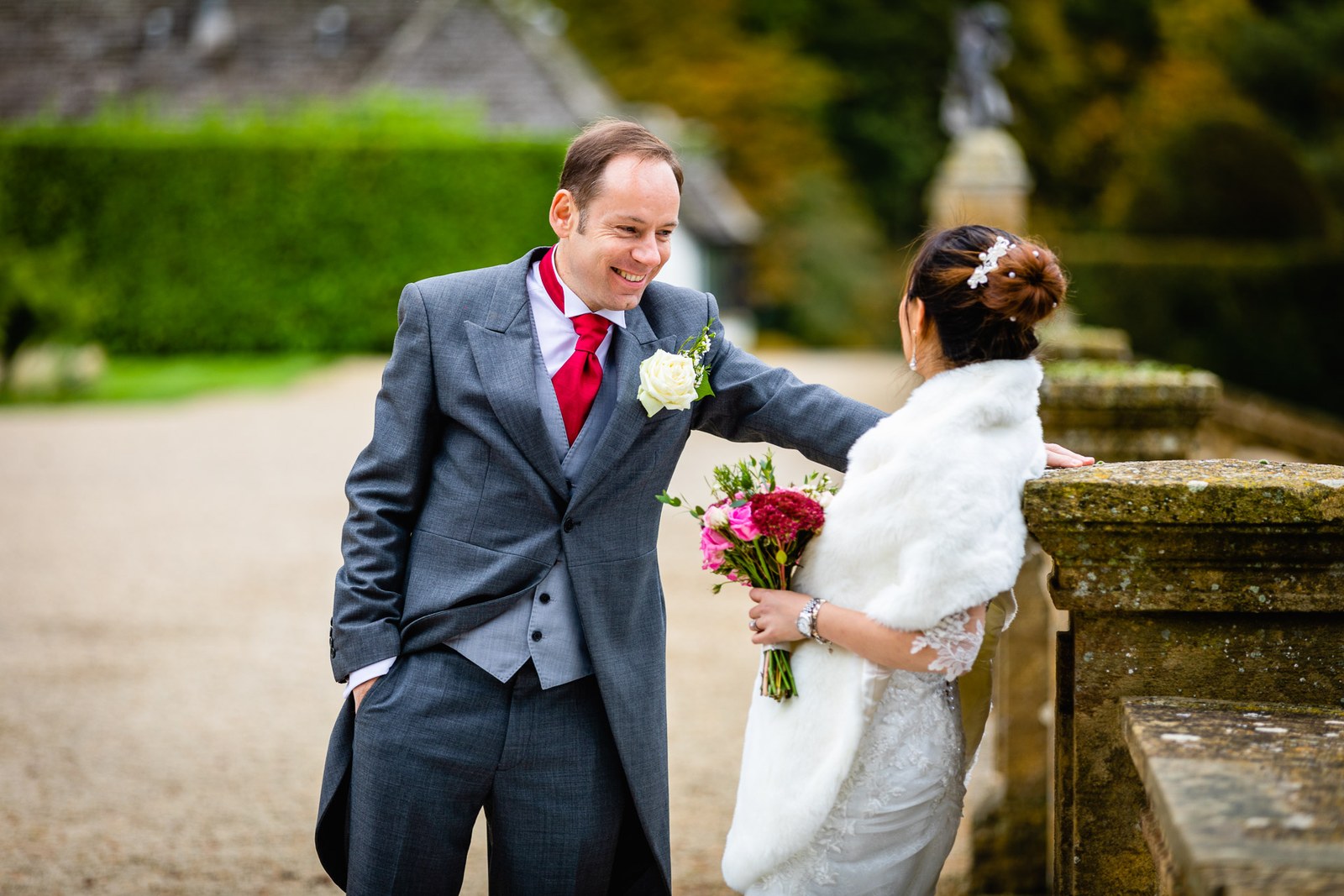 The groom smiling at the bride as she leans on the stone balustrade