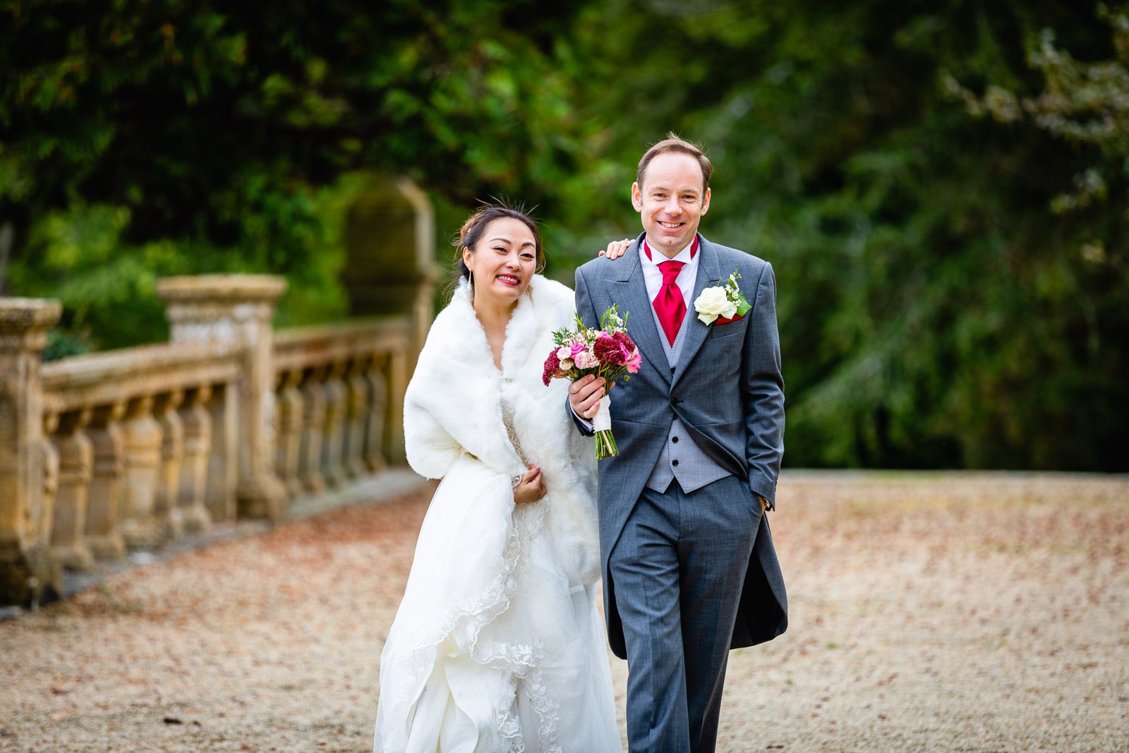 The couple walking together beside the terrace balustrade, bouquet in hand