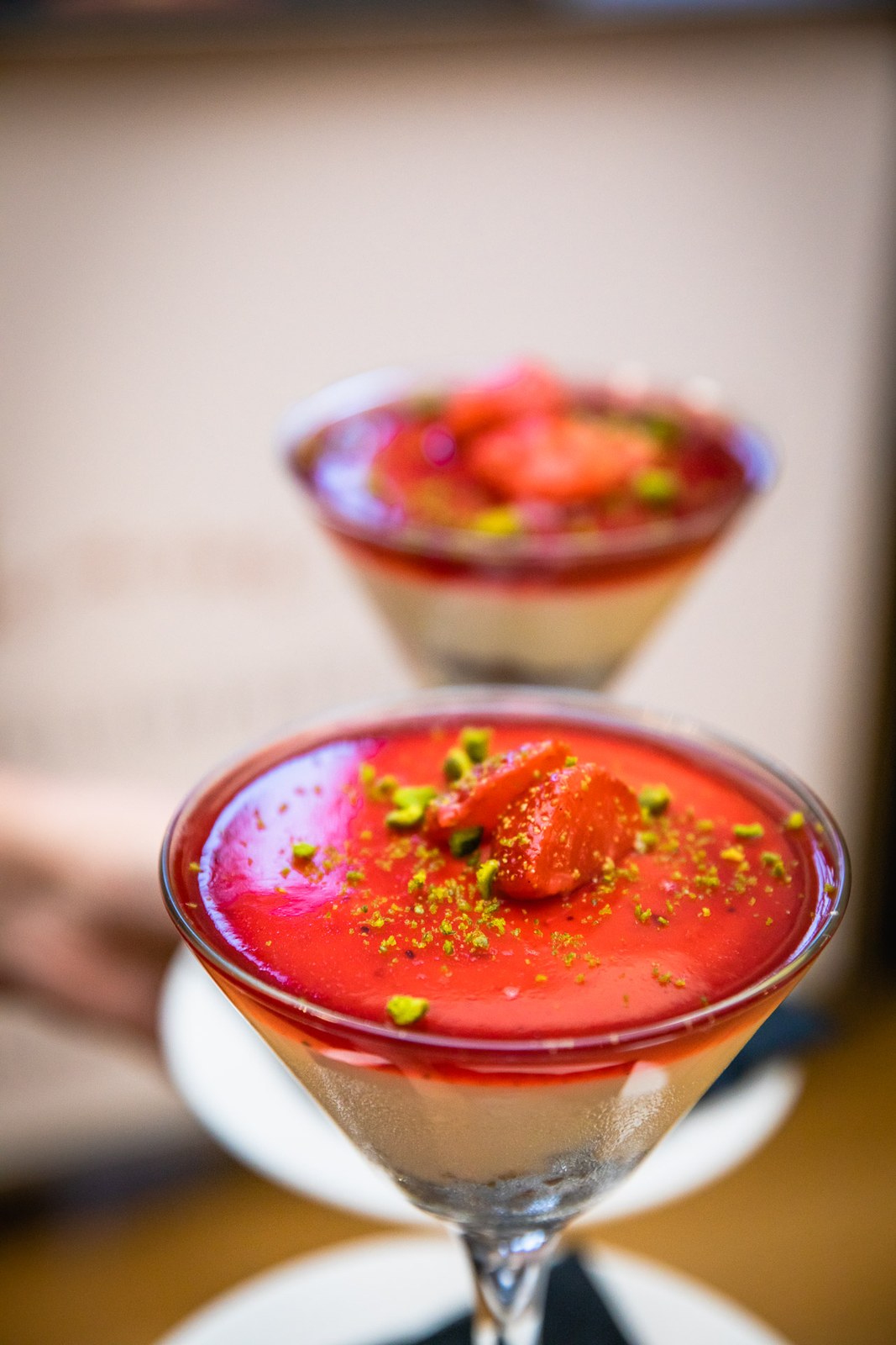 Close-up of strawberry desserts served in martini glasses, topped with pistachio