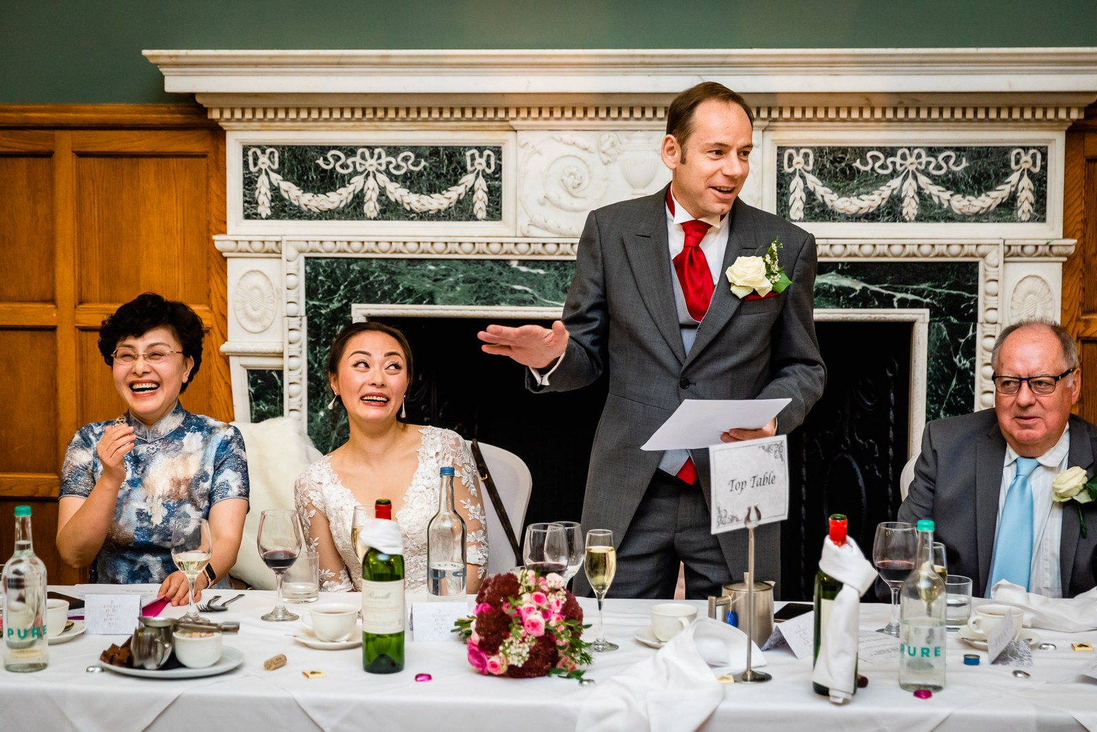 Groom giving his speech at the top table before the carved marble fireplace at Eynsham Hall