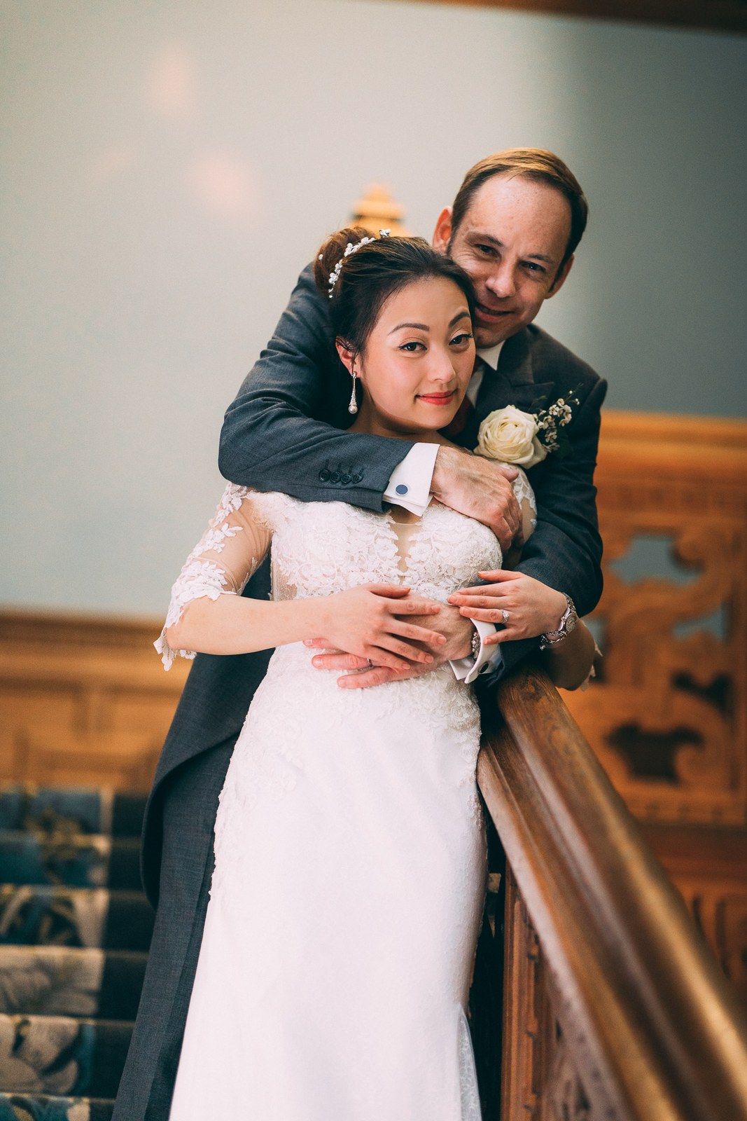 Bride and groom embracing at the reception banister, she leans back into him