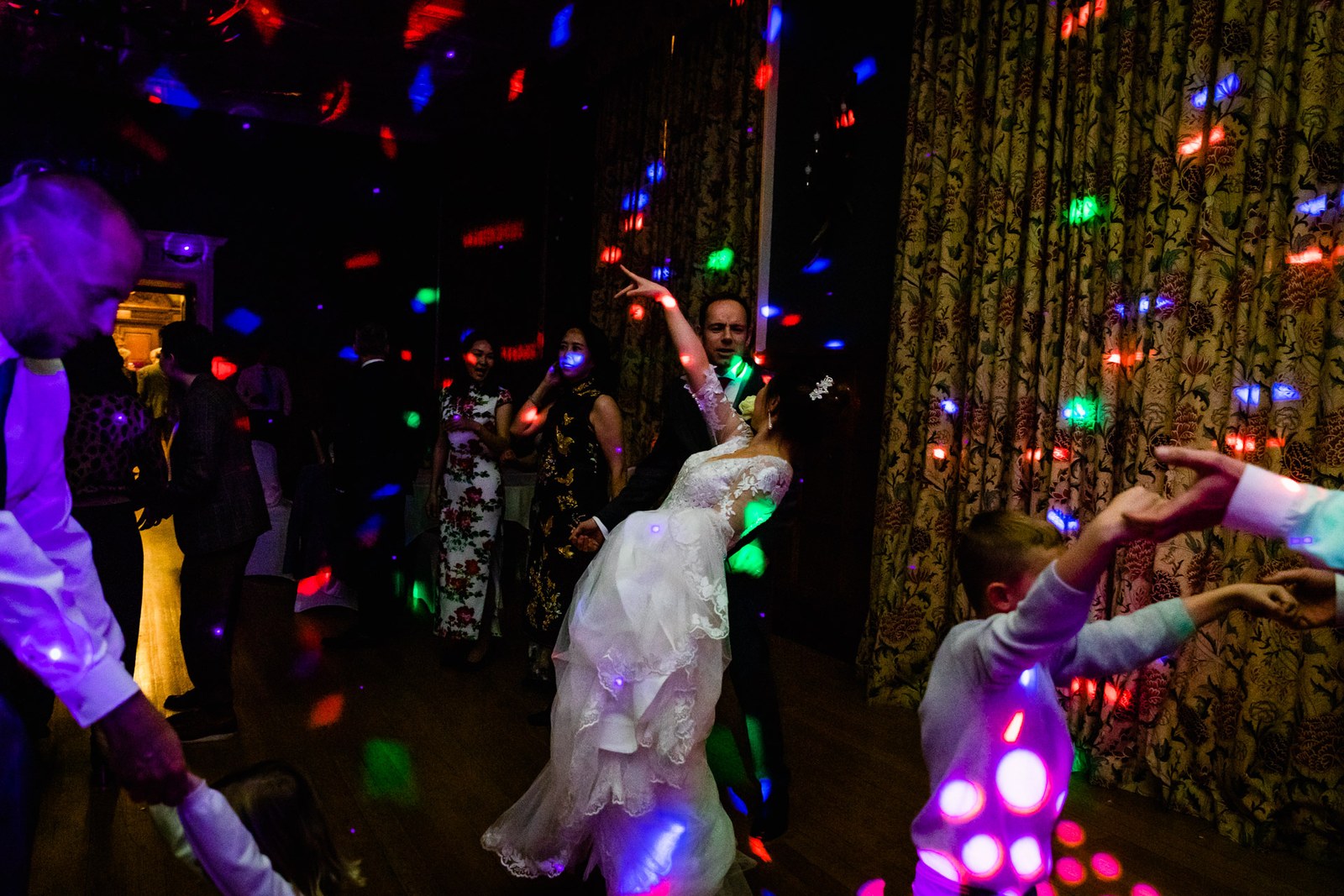 Bride dancing among her guests amid coloured disco lights