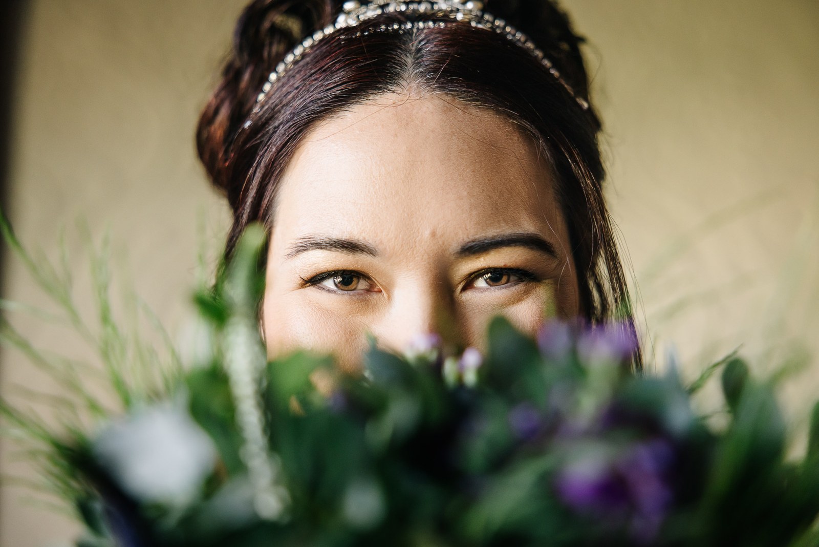The bride's eyes above a bouquet of purple blooms and trailing foliage