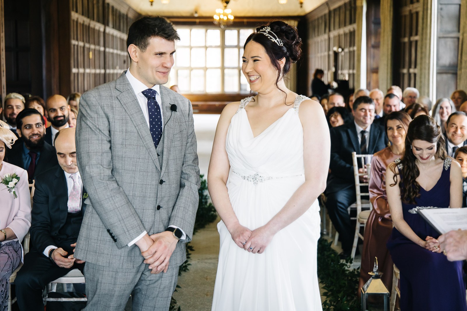 Bride and groom smiling at the front of the panelled gallery during the ceremony