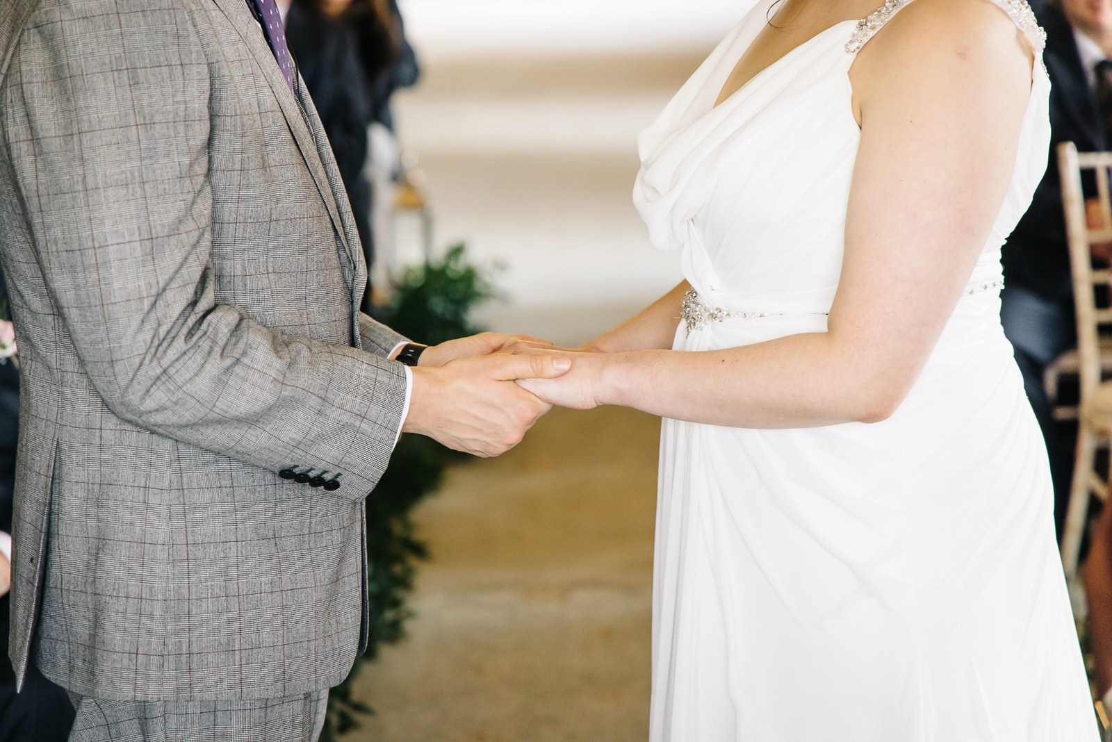 Close-up of the groom holding the bride's hand during the ceremony
