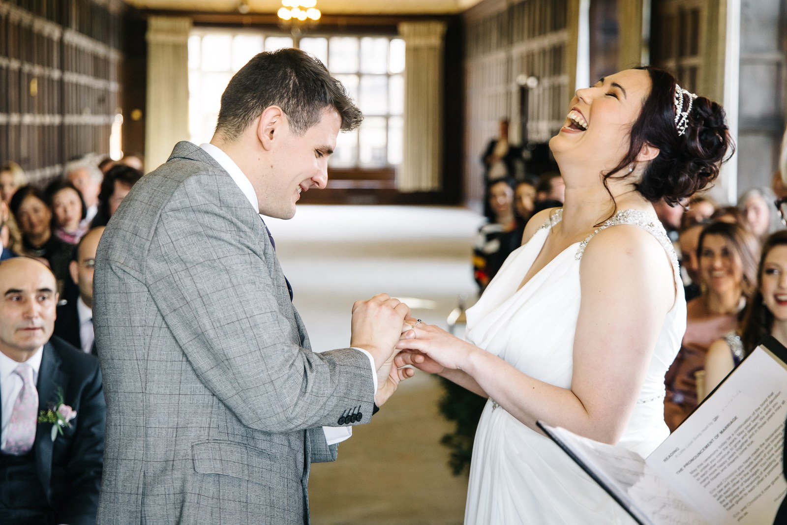 Bride laughing as the groom slides the ring onto her finger