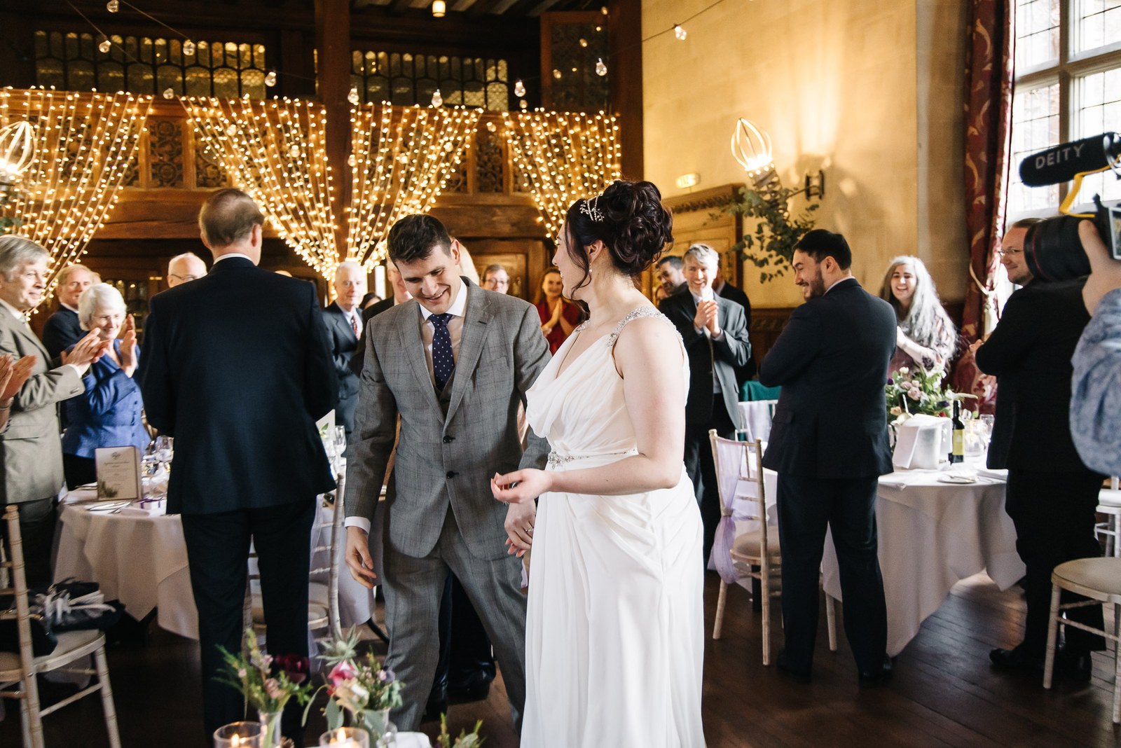 Bride and groom mingling with guests before a fairy-light backdrop in the reception room