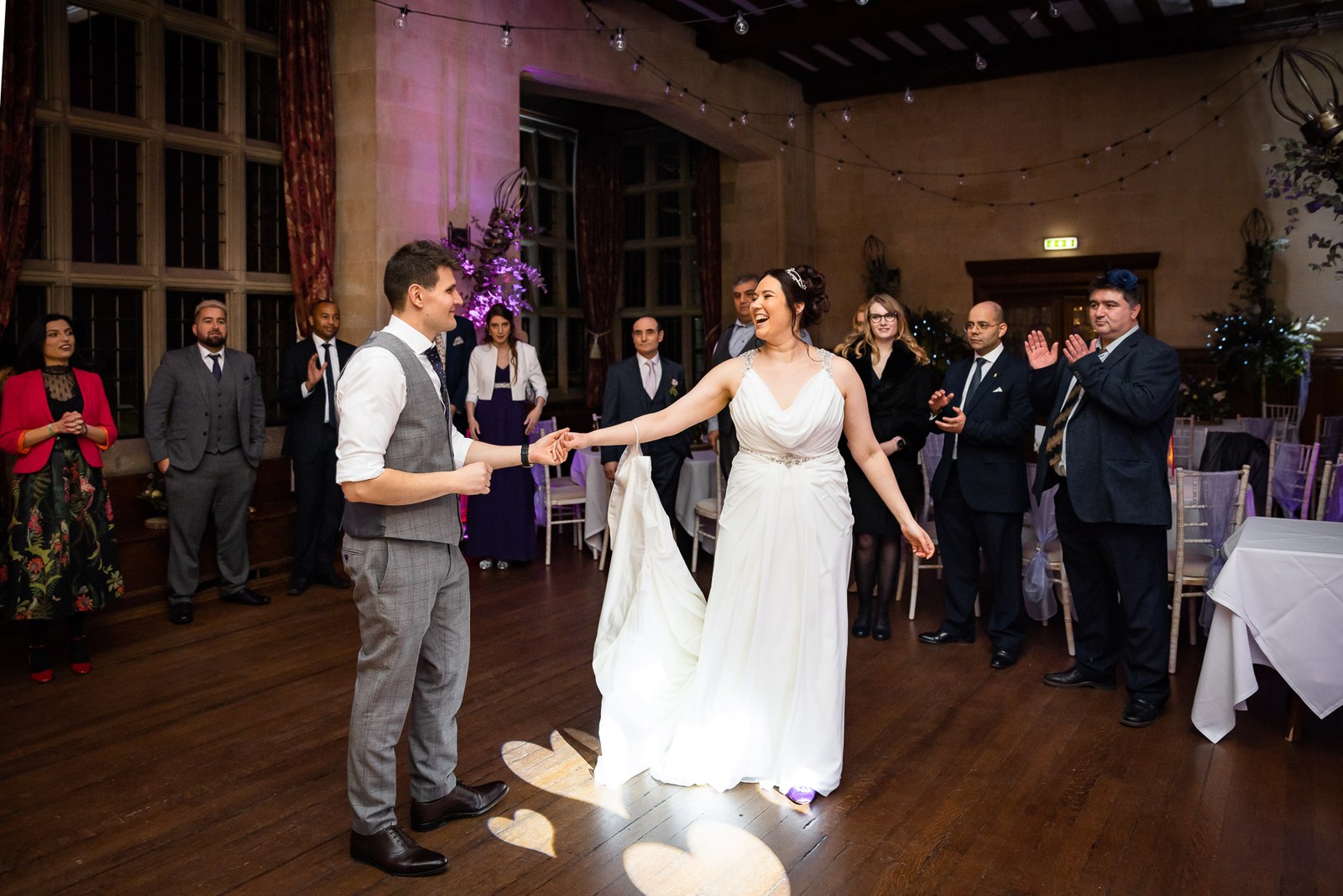 First dance under a heart-shaped spotlight as guests watch from the edges