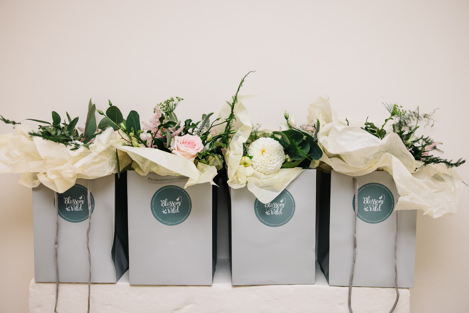 A row of grey florist bags with cream bouquets resting on top