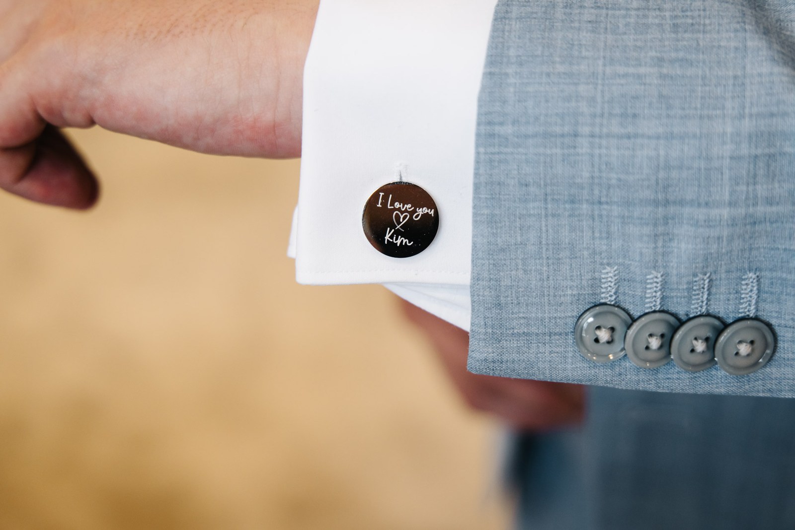 Close-up of a personalised cufflink engraved with a loving message on the groom's cuff