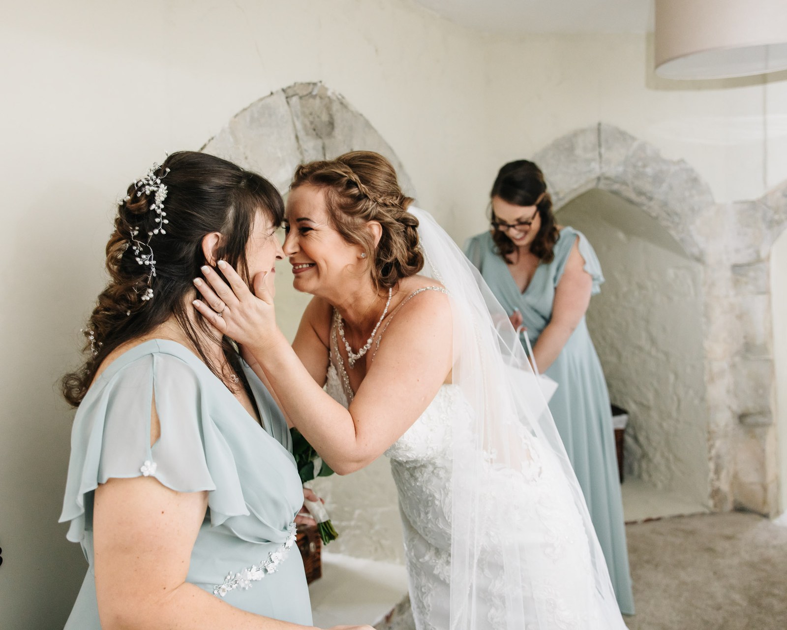 The bride and a bridesmaid sharing an emotional moment, foreheads together