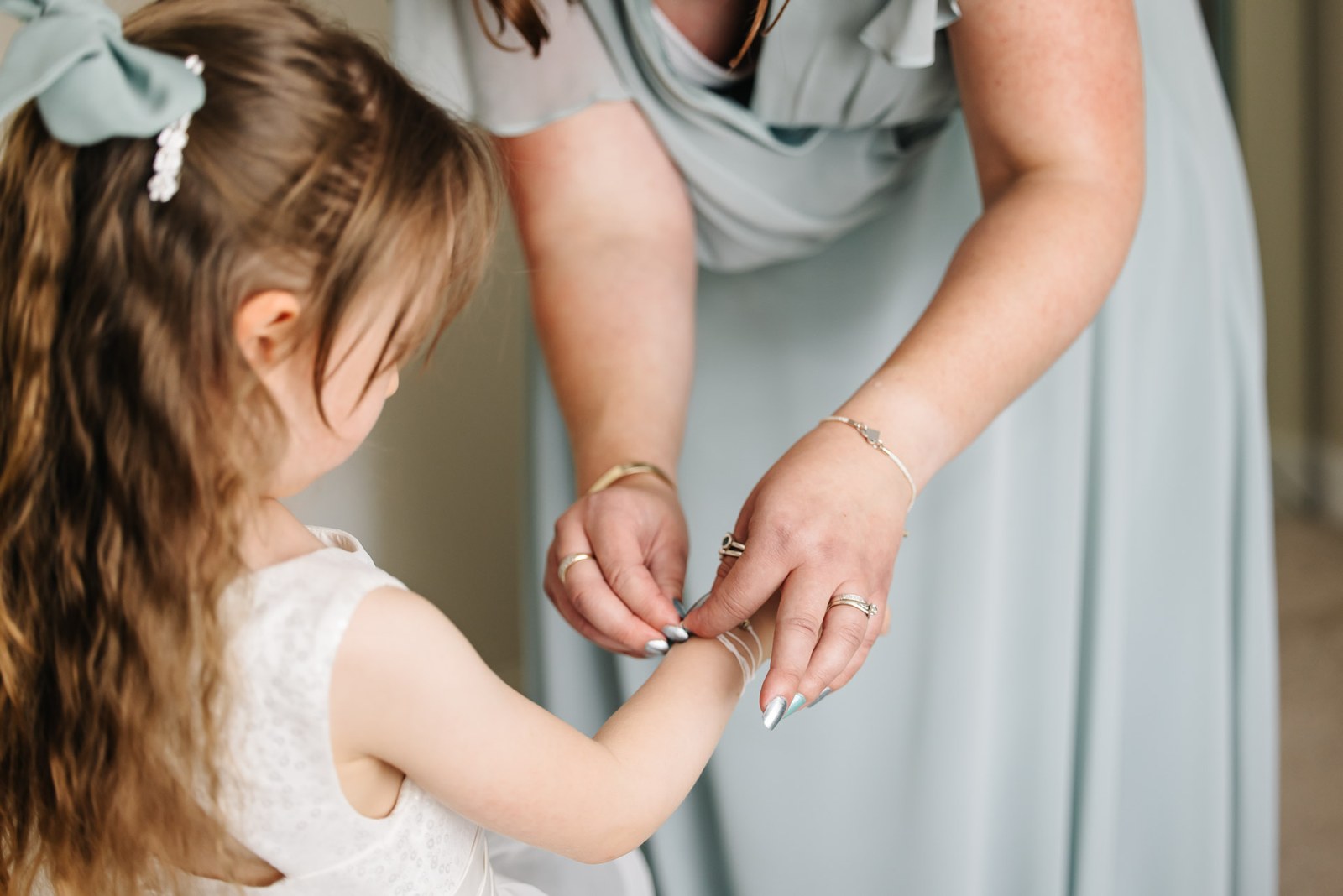 A flower girl having a delicate bracelet fastened around her wrist