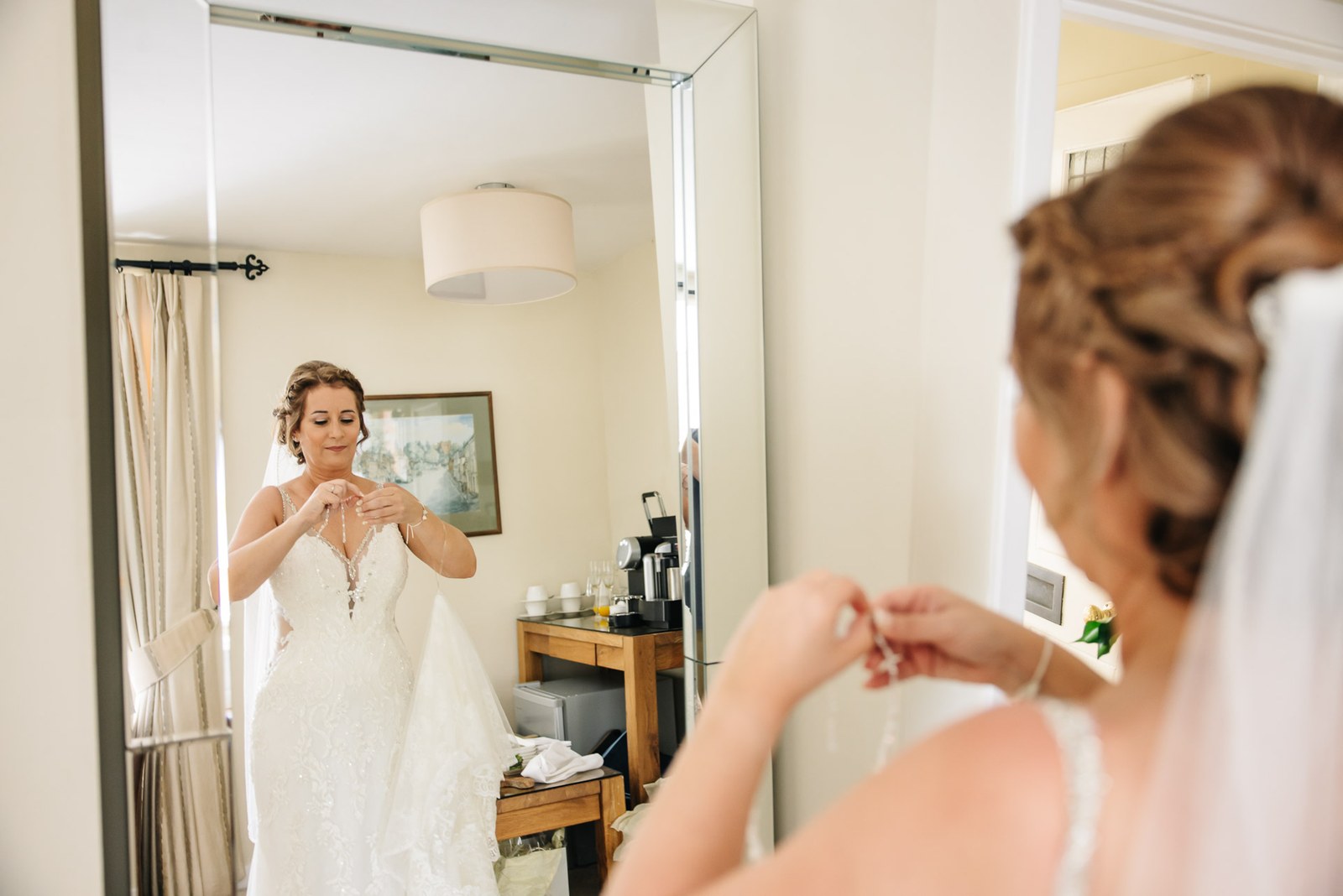 The bride adjusting her gown before a tall mirror