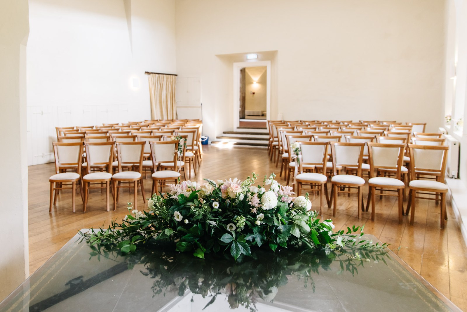 The ceremony room at Farnham Castle set with chairs and a low floral arrangement at the aisle