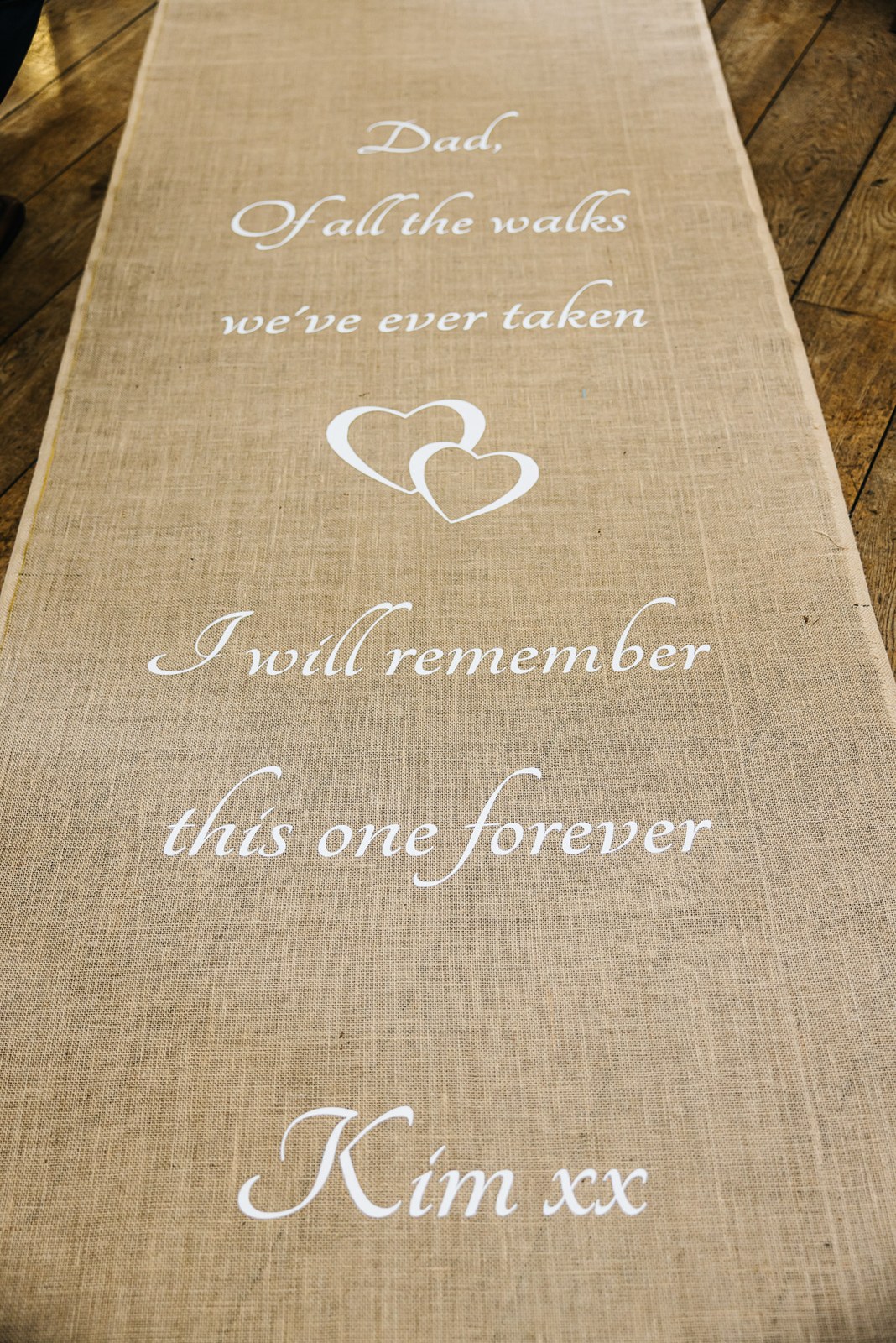 A hessian aisle runner printed with a heartfelt message from the bride to her father